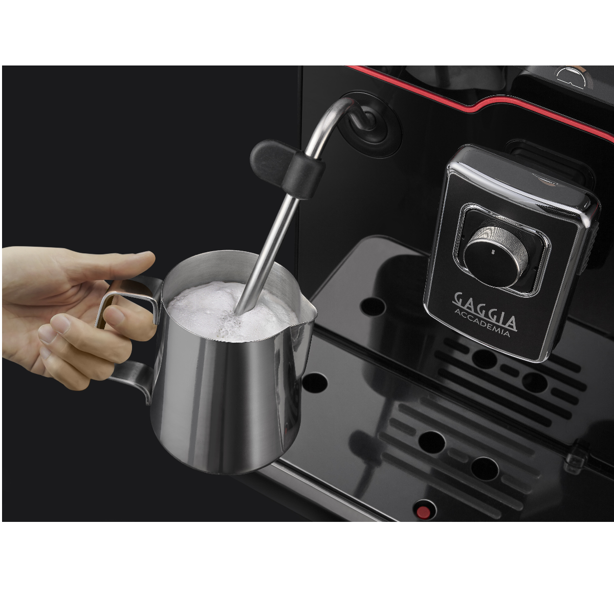 Eine Hand schäumt Milch mit einem Dampfstab neben einer Kaffeemaschine auf.