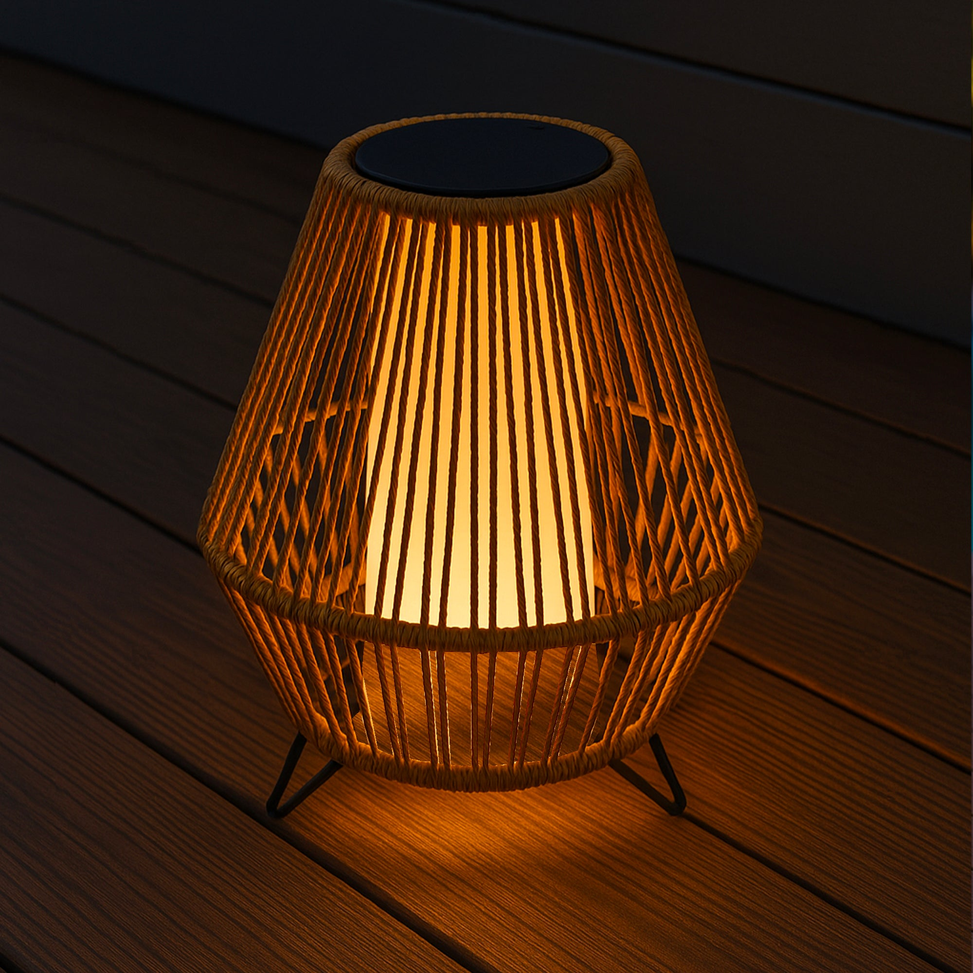 Solarbetriebene Laterne auf Holzterrasse. Gewebtes Design, gibt nachts warmes Licht ab.