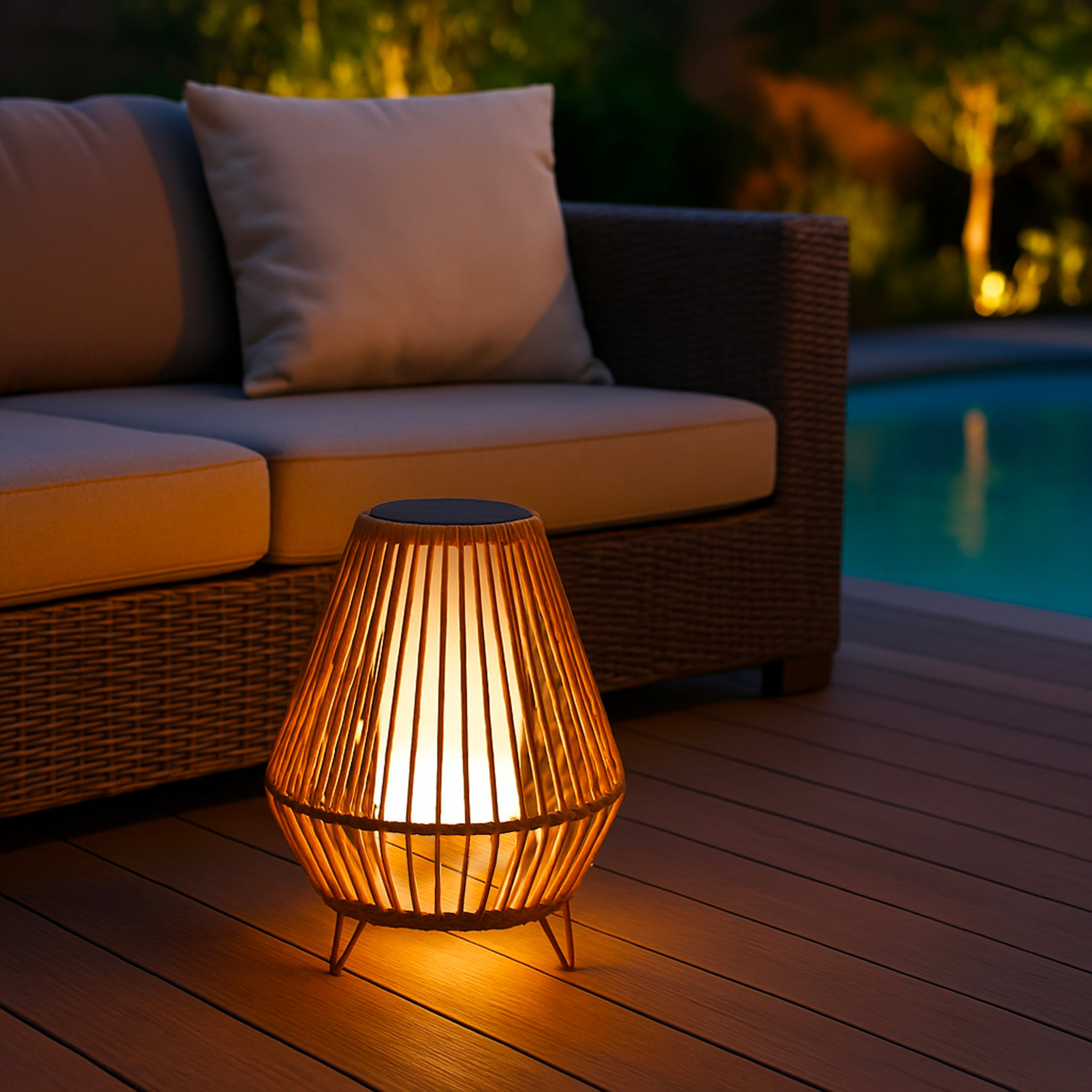 Eine Außenlampe, die neben einem Sofa und einem Pool leuchtet. Die Lampe ist aus Holz und gibt ein warmes Licht ab.