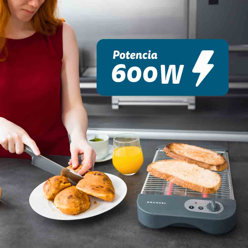 Donna taglia pane vicino al tostapane, bicchiere di succo e piatto di pane.