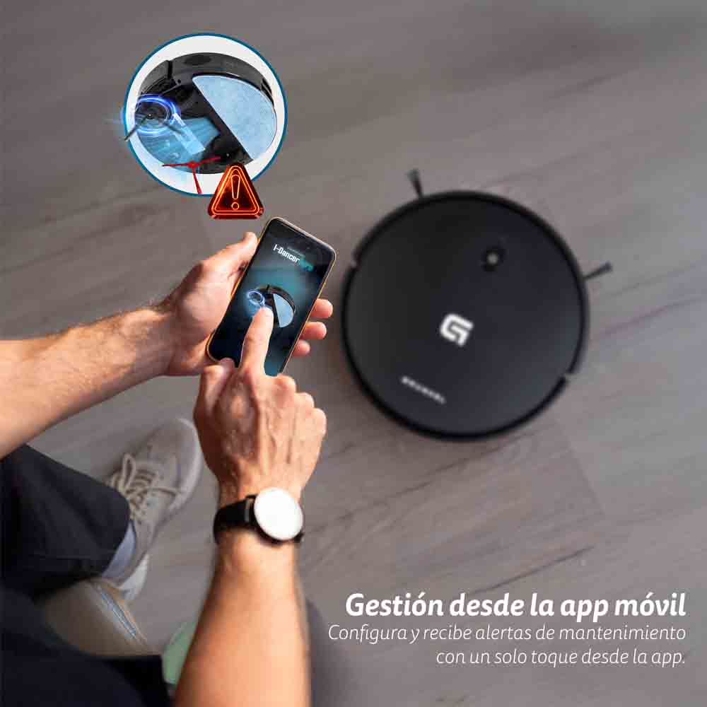 Una persona usa un smartphone para controlar un robot aspirador negro. Se muestra una alerta en la pantalla.