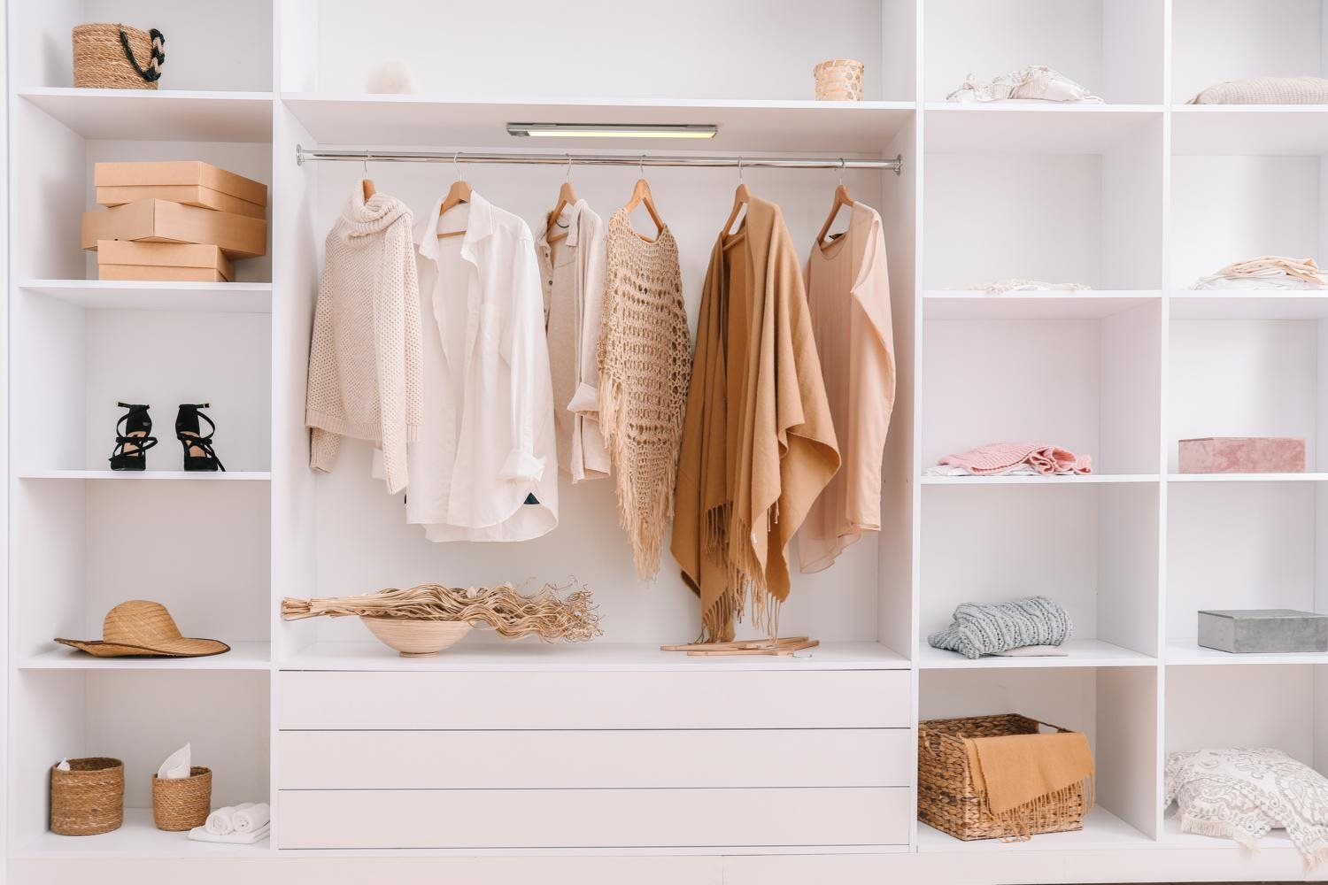 A white closet with clothes hanging and items on shelves.