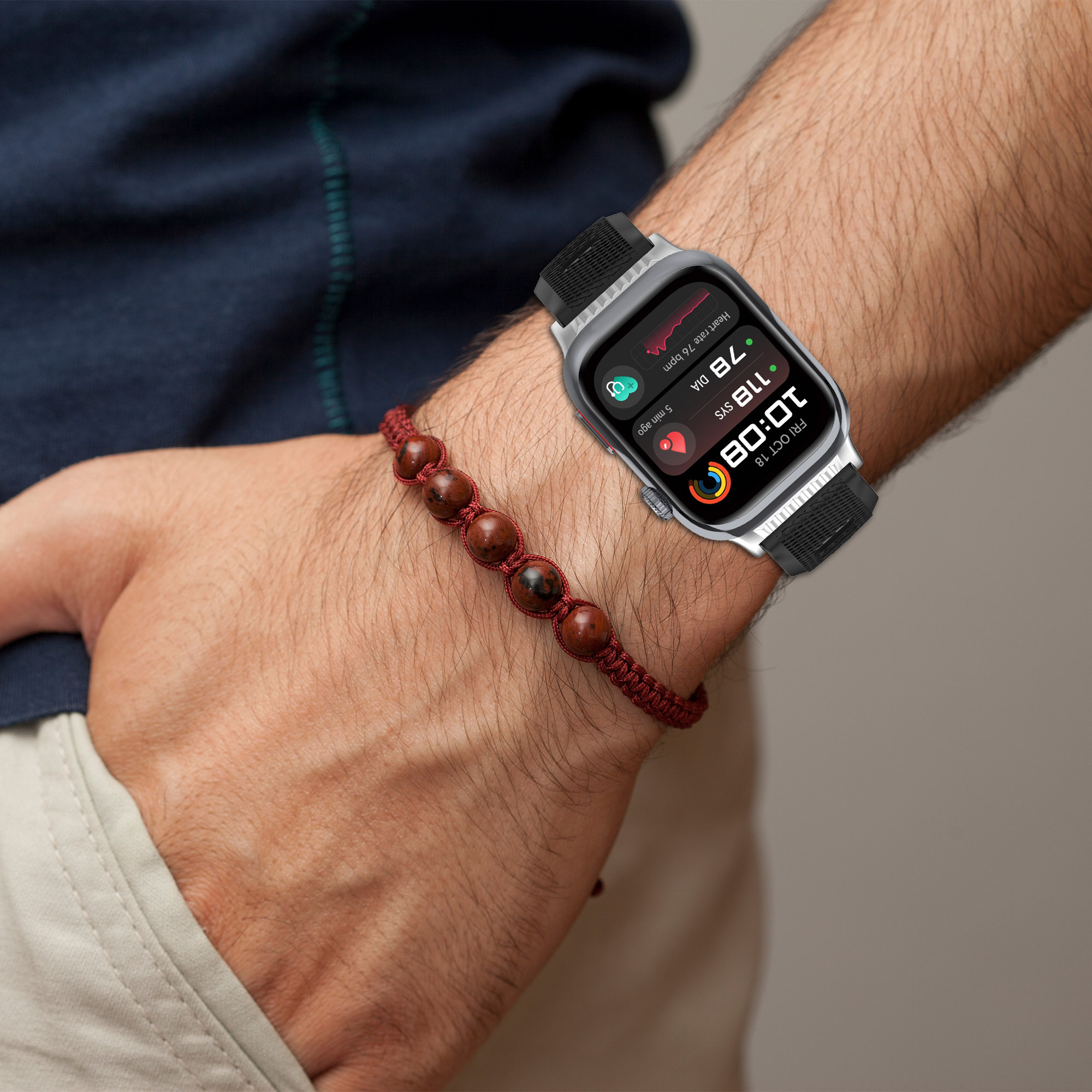 Das Handgelenk einer Person mit einer Smartwatch und einem roten Perlenarmband.