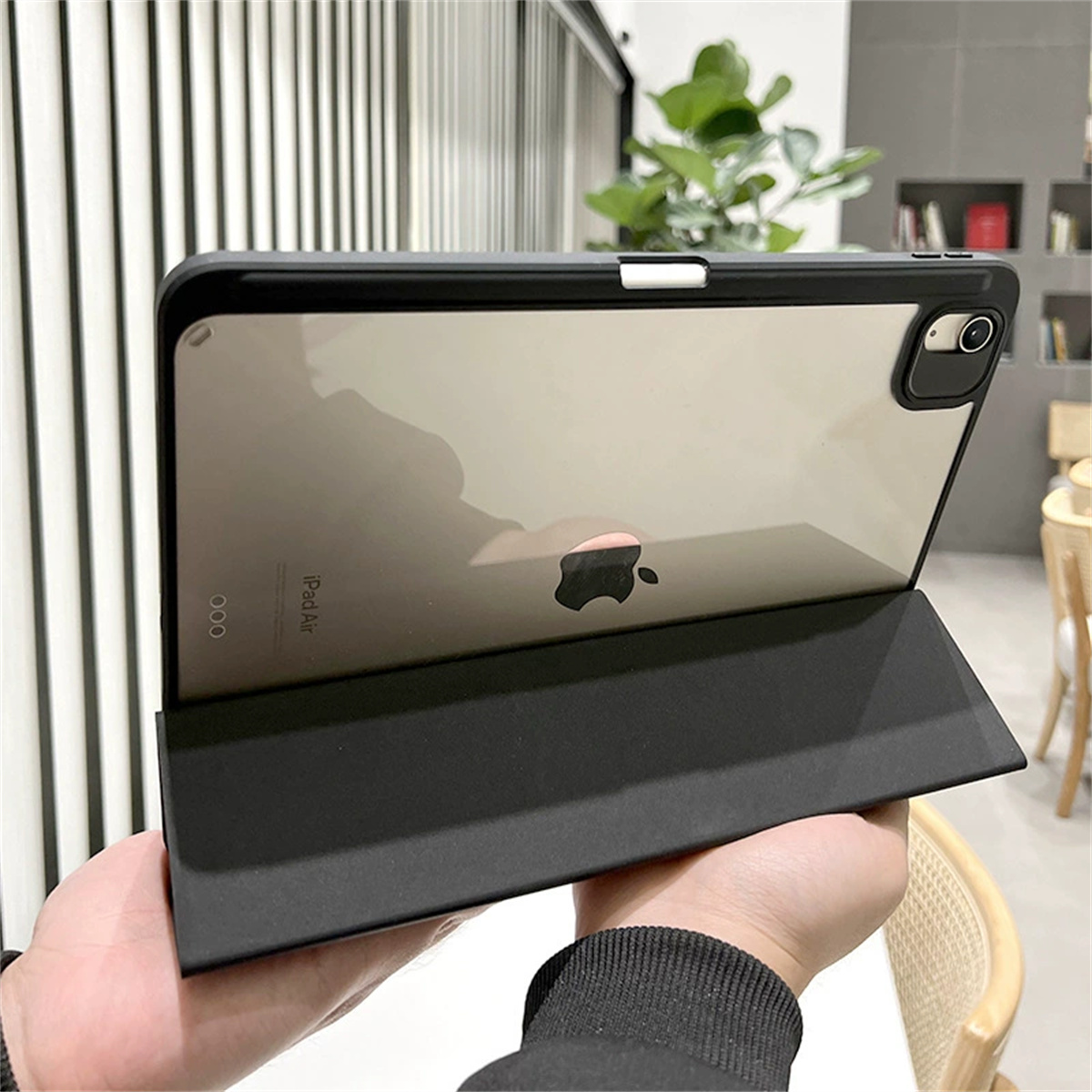 Ein iPad Air in einem schwarzen Gehäuse, teilweise geöffnet, von einer Person gehalten, zeigt den Bildschirm.