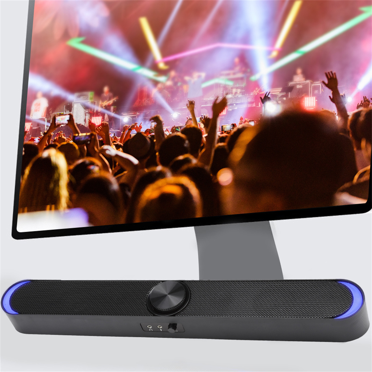 Ein schwarzer Lautsprecher mit blauen Lichtern vor einem Monitor, der eine Konzertszenen zeigt.