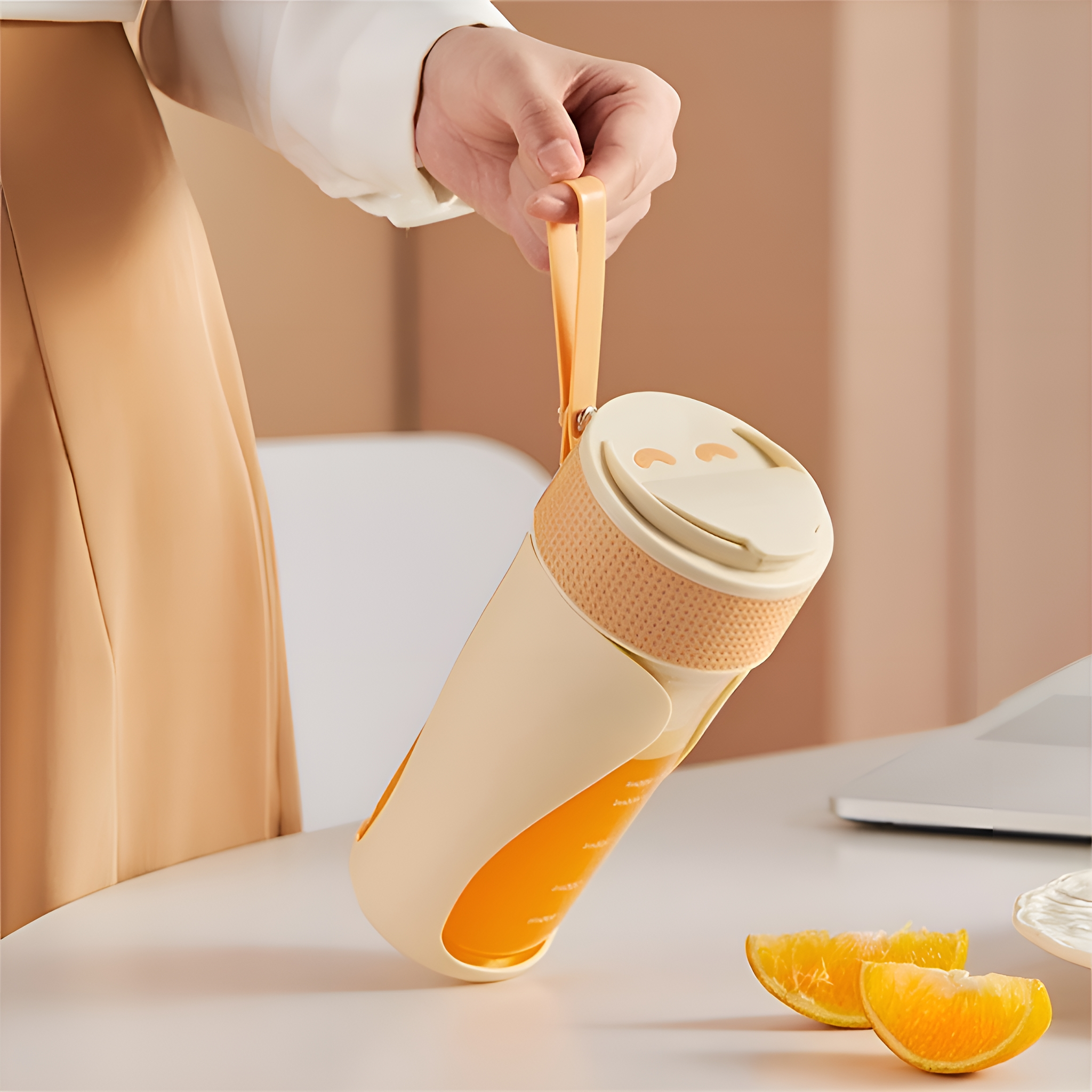 Hand hält eine beige-orangefarbene Wasserflasche, Orangenscheiben auf dem Schreibtisch.