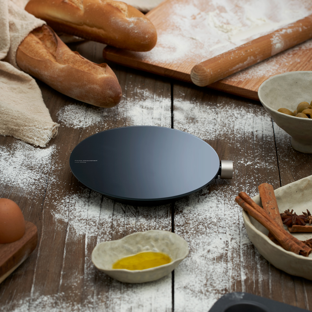 Eine Küchenwaage auf Holzoberfläche mit Mehl, Brot und Zutaten, bereit zum Backen.