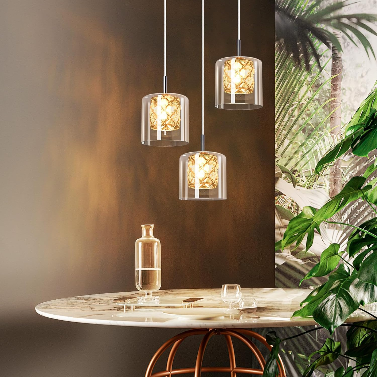 Trzy lampy wiszące z cylindrycznymi szklanymi kloszami wiszą nad stołem, tło z liści palmowych.