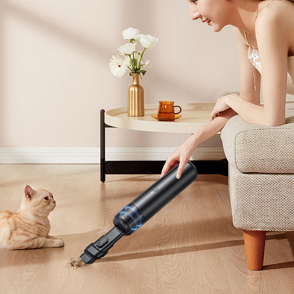 Frau benutzt schwarzen Staubsauger auf dem Boden. Eine Katze schaut zu. Beige und weißer Raum.
