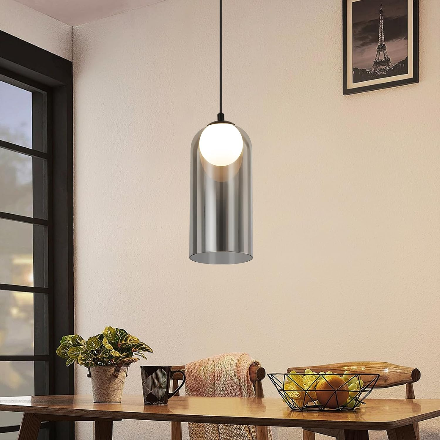 Moderne Hängeleuchte über einem Holztisch mit Pflanze, Tasse und Obstschale.