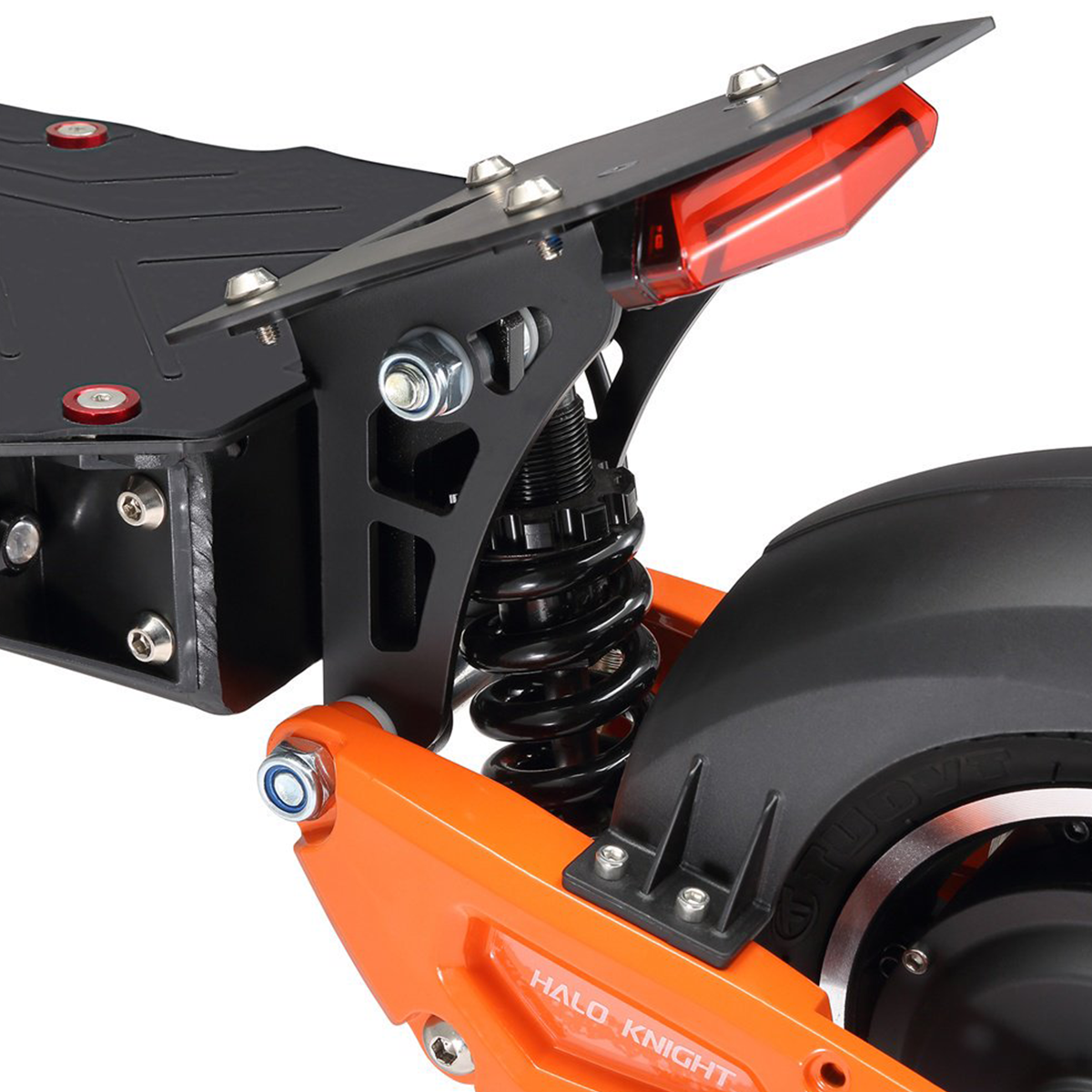 Zbliżenie tyłu czarno-pomarańczowej hulajnogi, pokazujące koło, zawieszenie i światło.