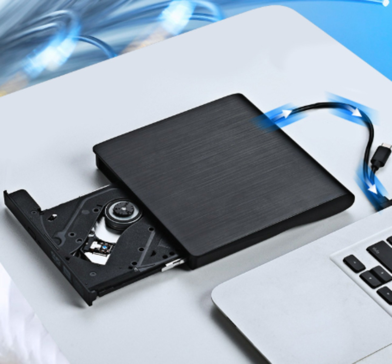 Ein schwarzes CD-Laufwerk mit teilweise eingelegter CD. Ein blaues Kabel führt vom Laufwerk zu einem Laptop.