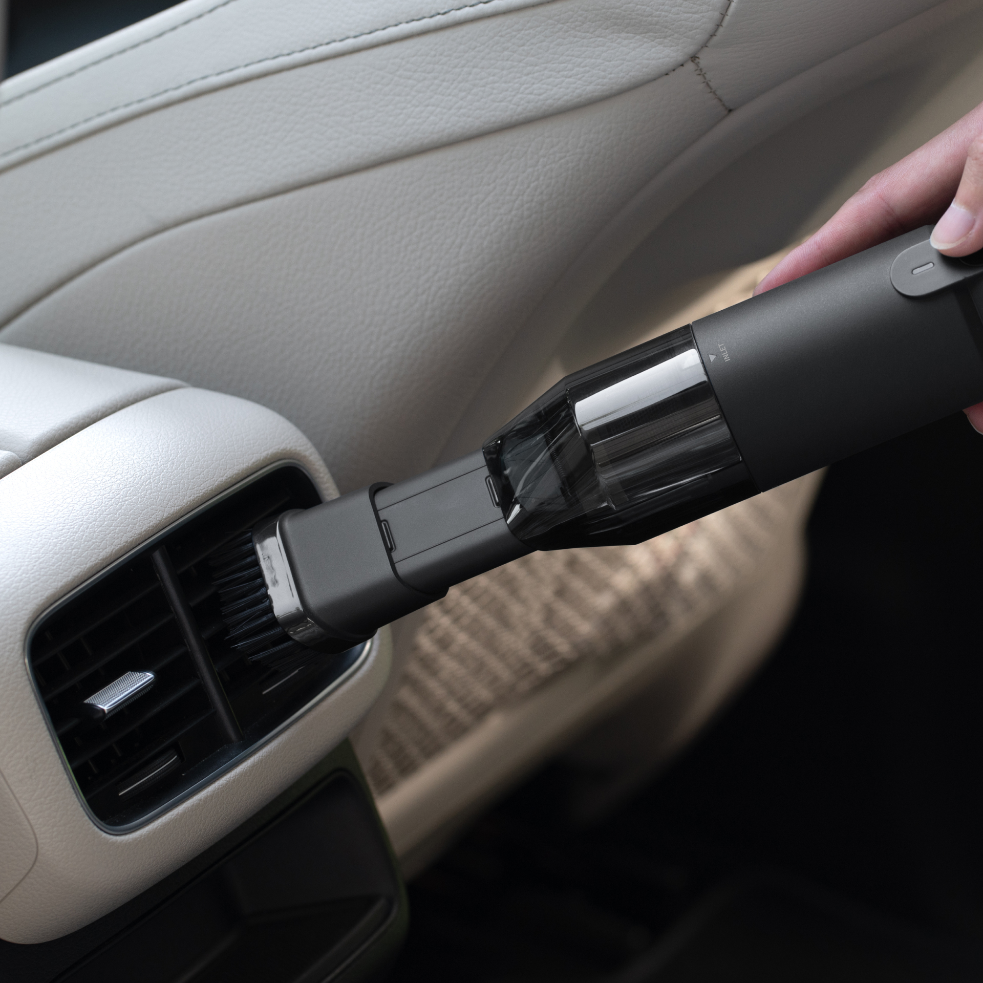 Persona che usa un'aspirapolvere per auto nera all'interno di un veicolo.