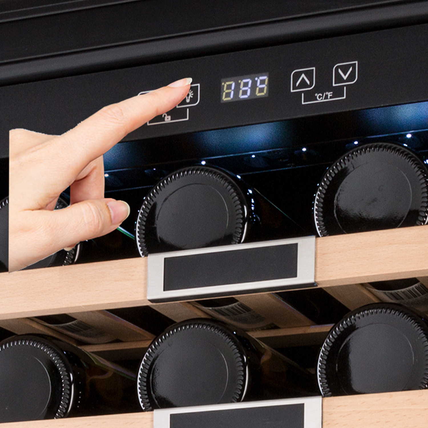 Eine Hand berührt die Digitalanzeige eines Weinkühlers mit Temperatur.