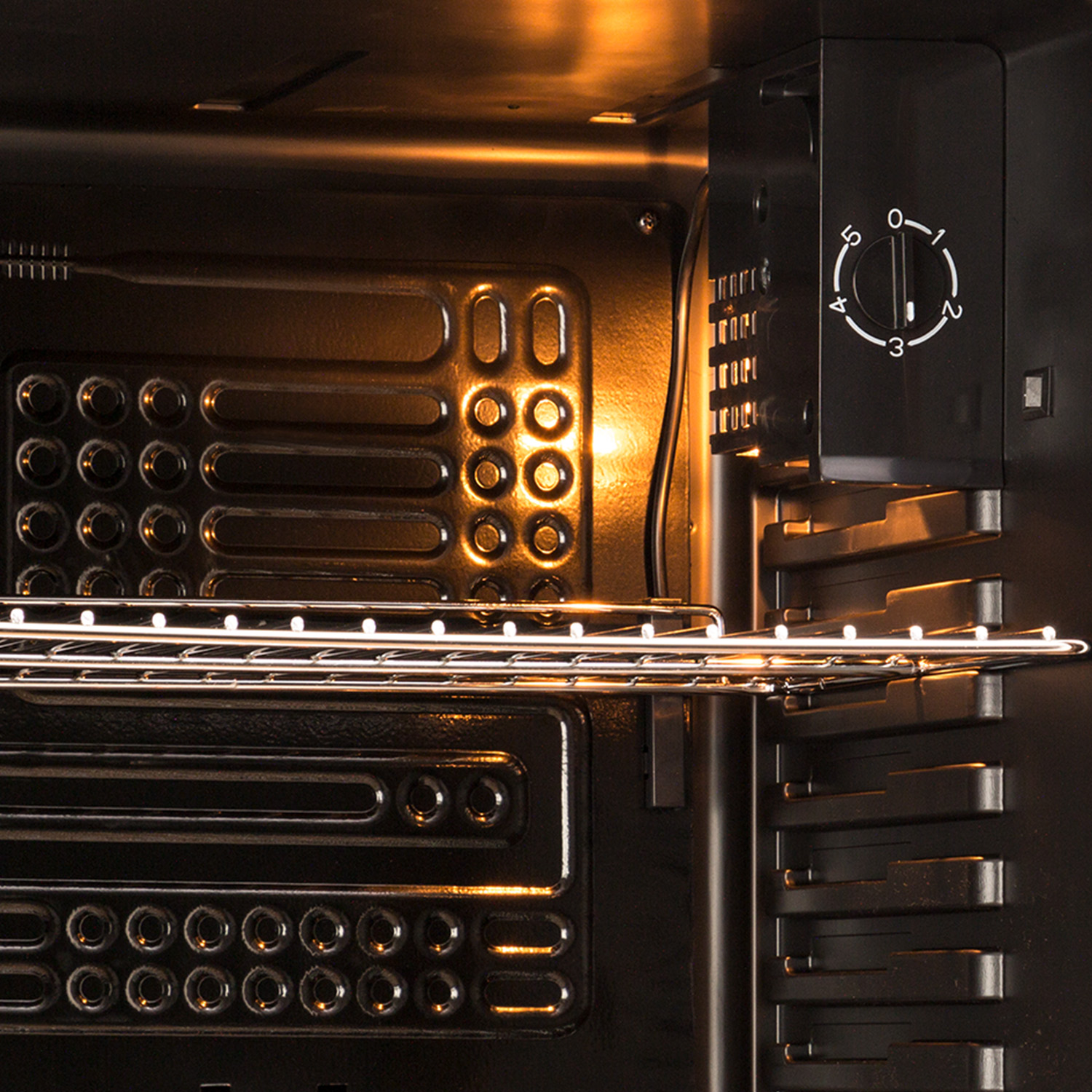 Interior de un horno con una rejilla. El dial está configurado en 3. Luz cálida en el interior.