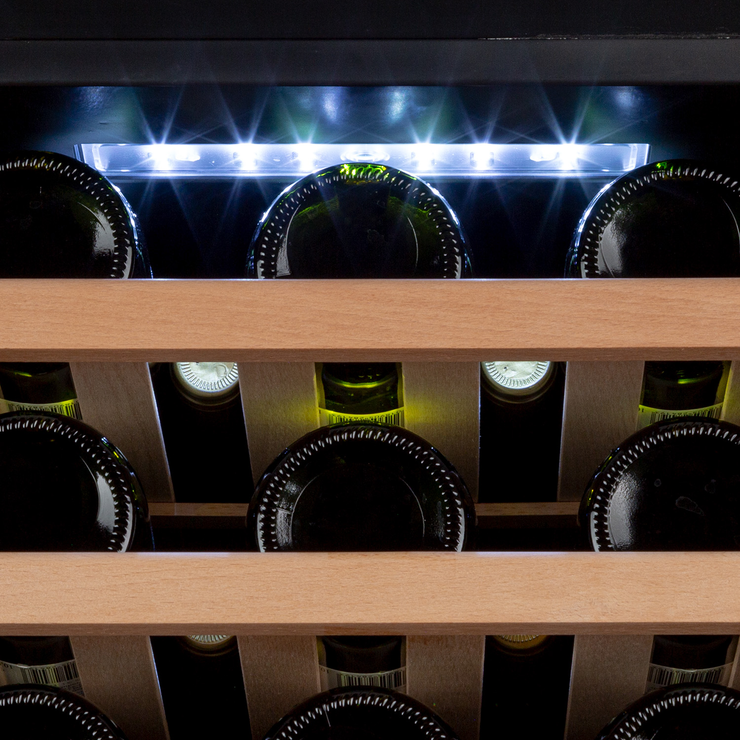 Interno di una cantinetta, con bottiglie di vino su ripiani in legno. Luci dall'alto.