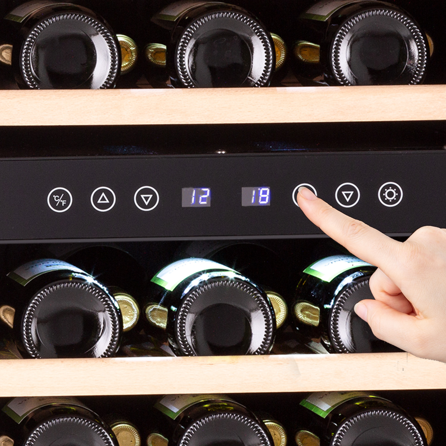 Cantinetta con bottiglie all'interno. Una mano preme un pulsante per regolare la temperatura. Porta a vetro.