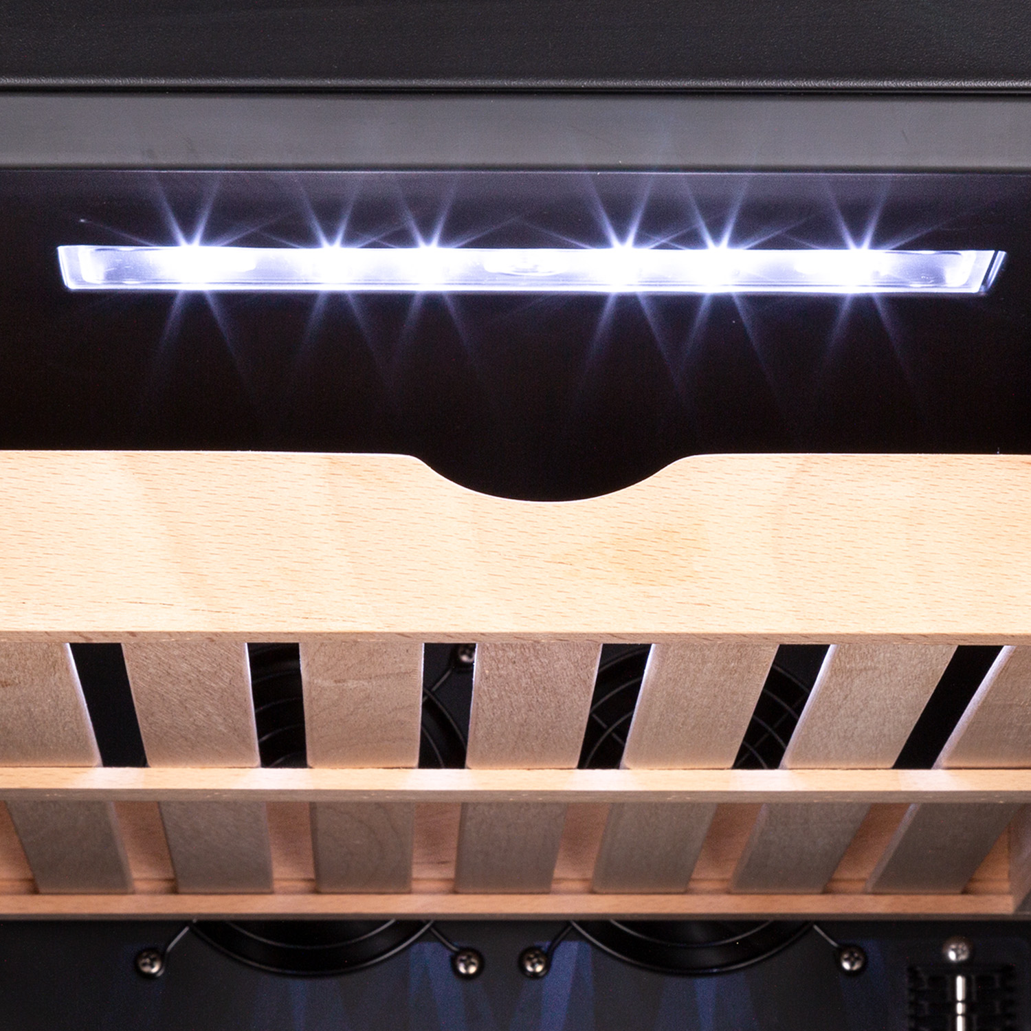 Interno di una cantinetta, con ripiani in legno e una fila di luci LED luminose.