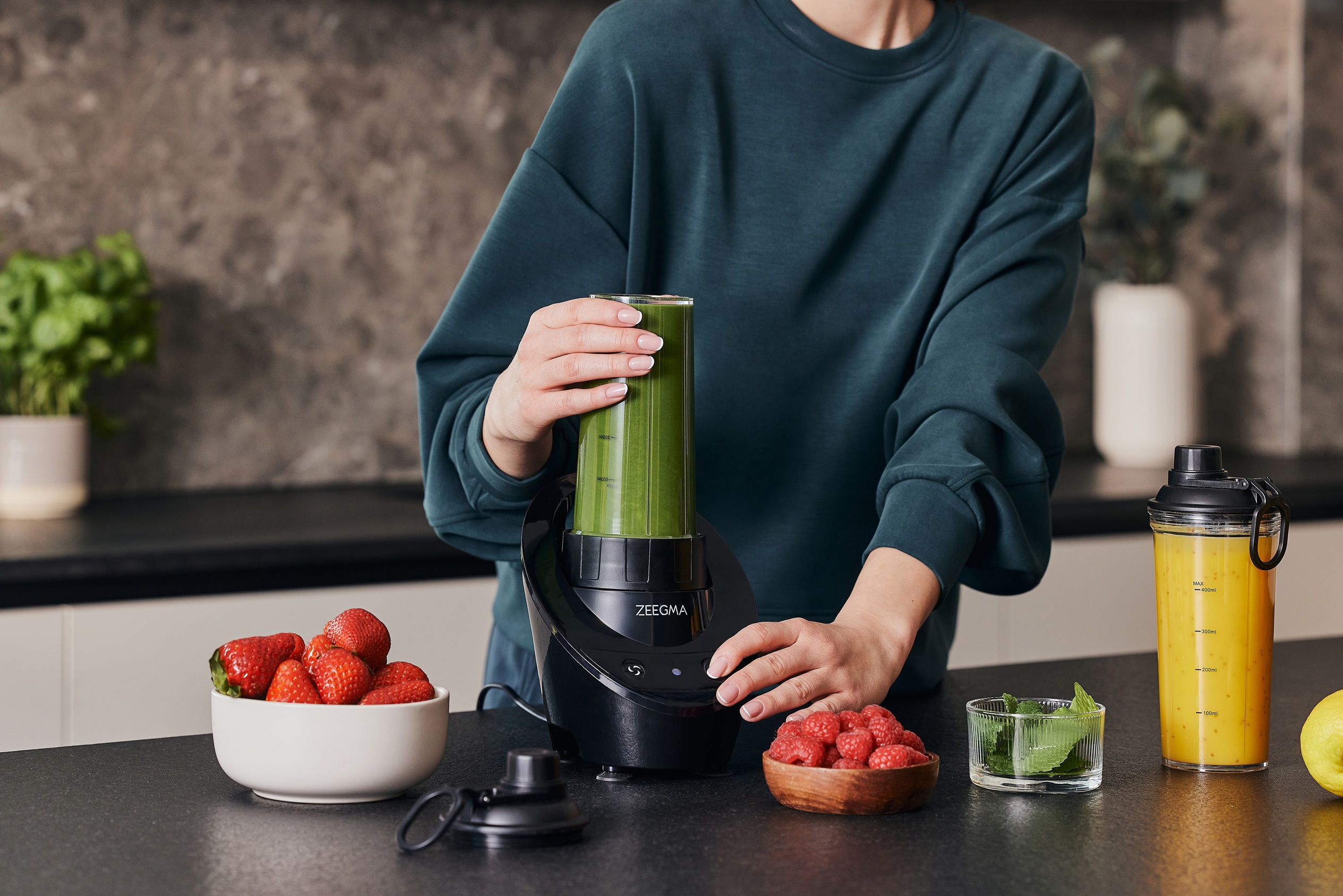 Osoba używająca blendera z owocami na stole.