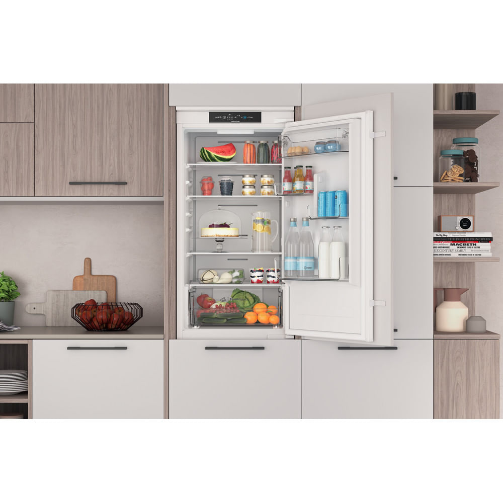 Interior de refrigerador mostrando estantes con alimentos. Puerta abierta.