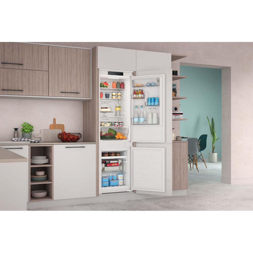 Un refrigerador blanco con las puertas abiertas, revelando estantes con frutas, verduras y botellas.