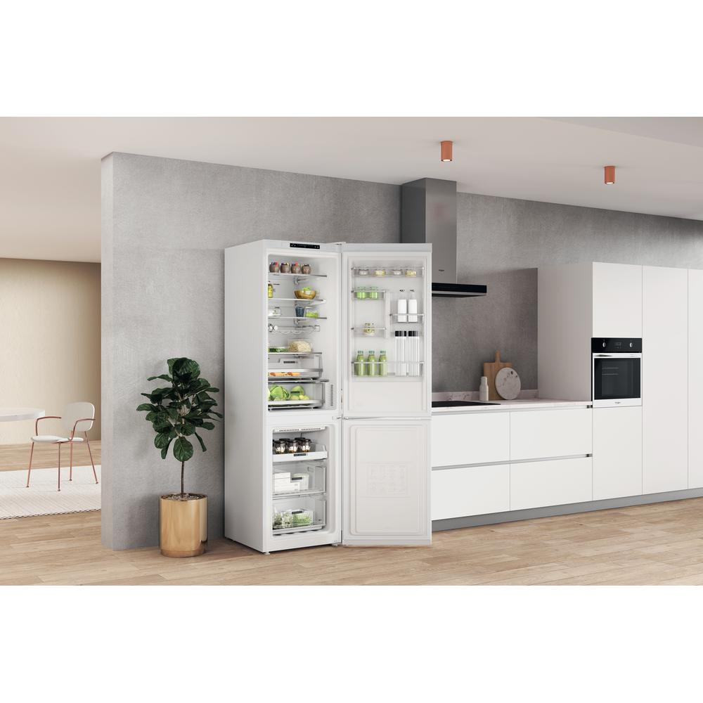 Frigorífico blanco con la puerta abierta, mostrando estantes de comida en una cocina moderna.