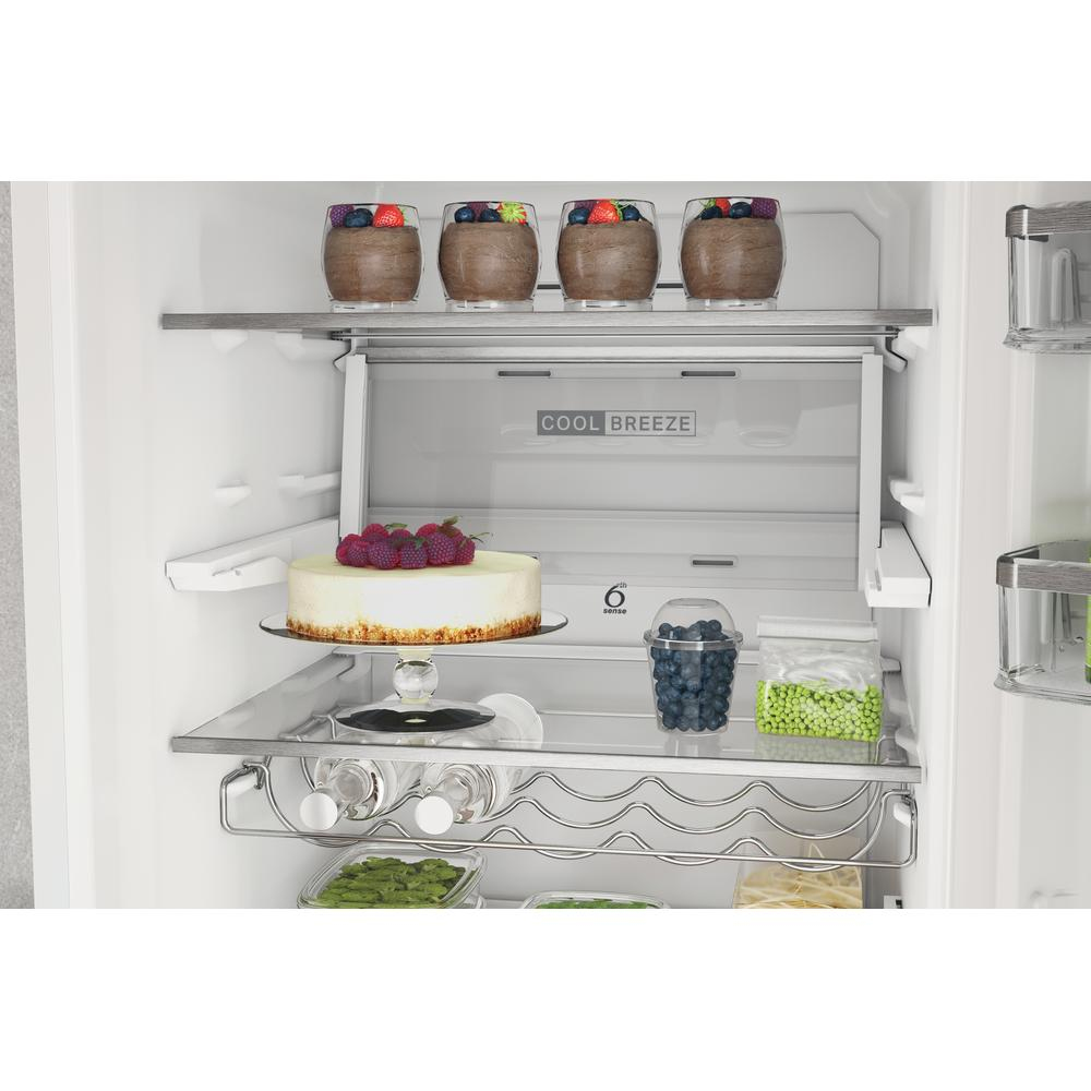 Interior de refrigerador con alimentos en estantes: postres en vasos, pastel, frutas y verduras.