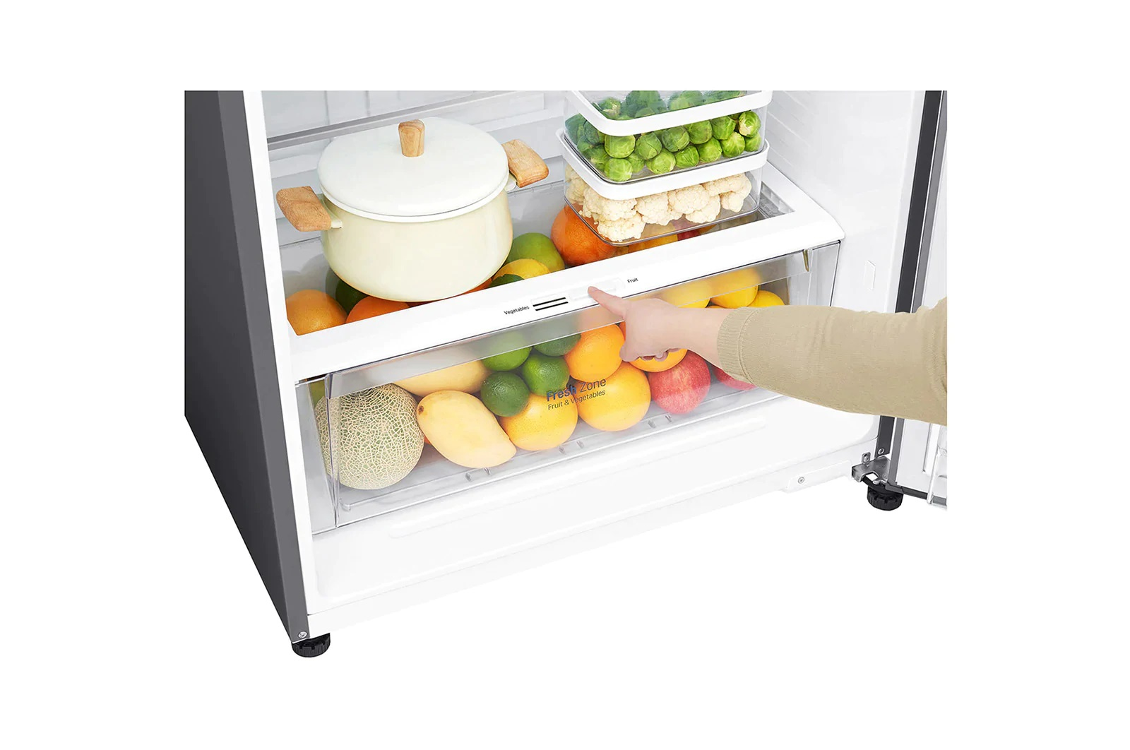 Una persona regola il cassetto all'interno di un frigorifero. Frutta e verdura visibili. Lo sfondo è bianco.