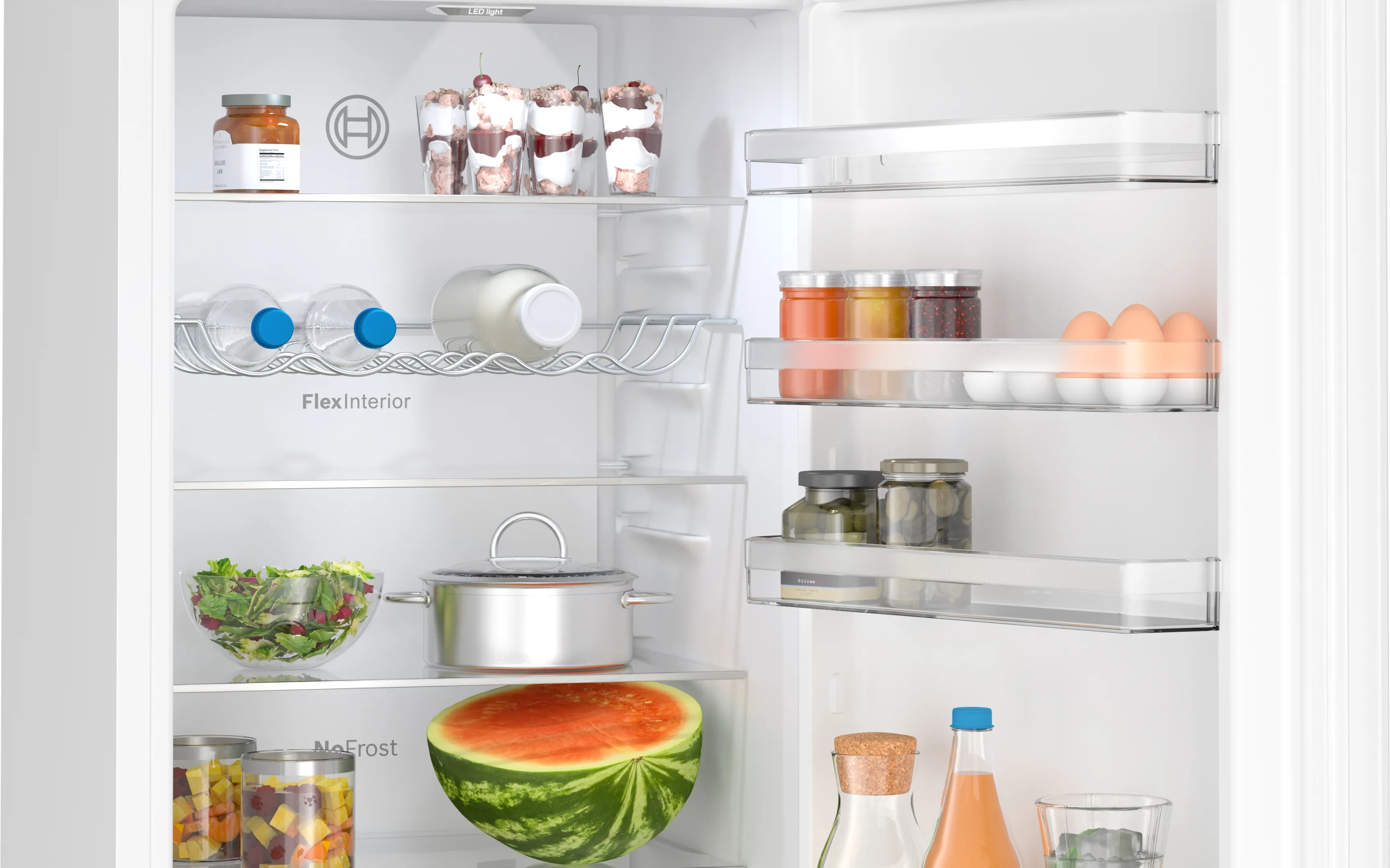 Otwarta lodówka z półkami pełnymi jedzenia: słoiki, butelki, owoce, warzywa i dania.