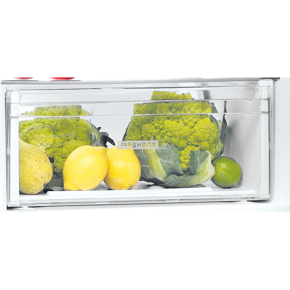 Primer plano de un cajón de refrigerador lleno de coliflor, limones, una pera y una lima.