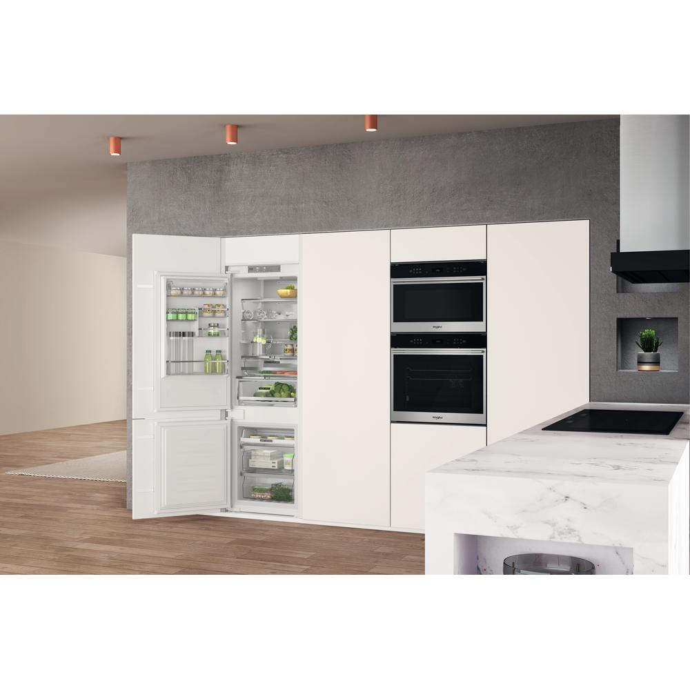 Kitchen with white cabinets, integrated appliances, and a refrigerator open.