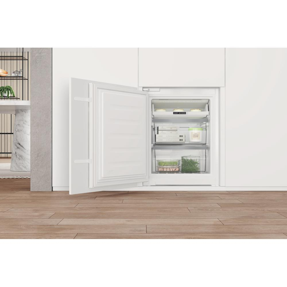 White built-in freezer with open door, showing shelves with food.
