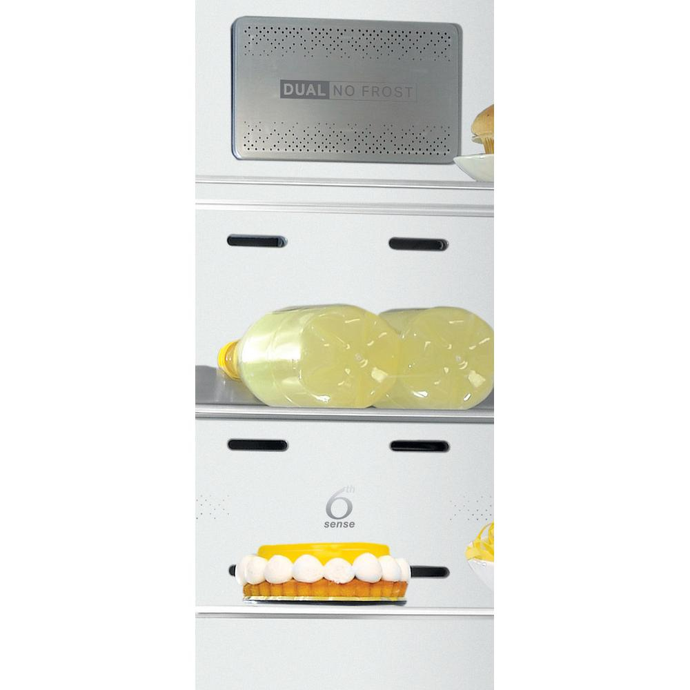 Interior de refrigerador con estantes, cajones y el símbolo 6th sense. Contiene botellas de jugo.
