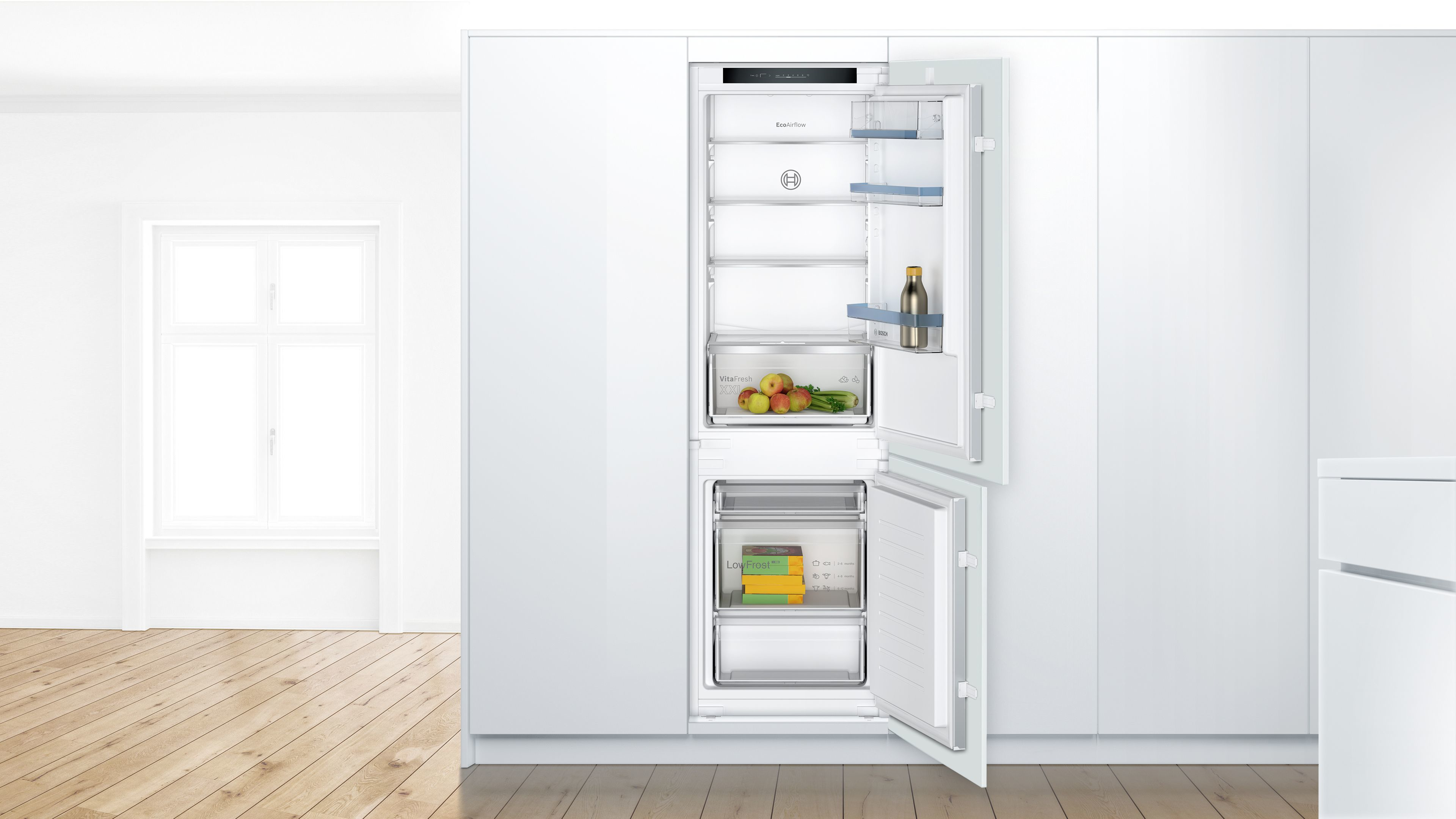 Moderner weißer Einbaukühlschrank. Geöffnet, zeigt Regale, Schubladen und Lebensmittel darin.