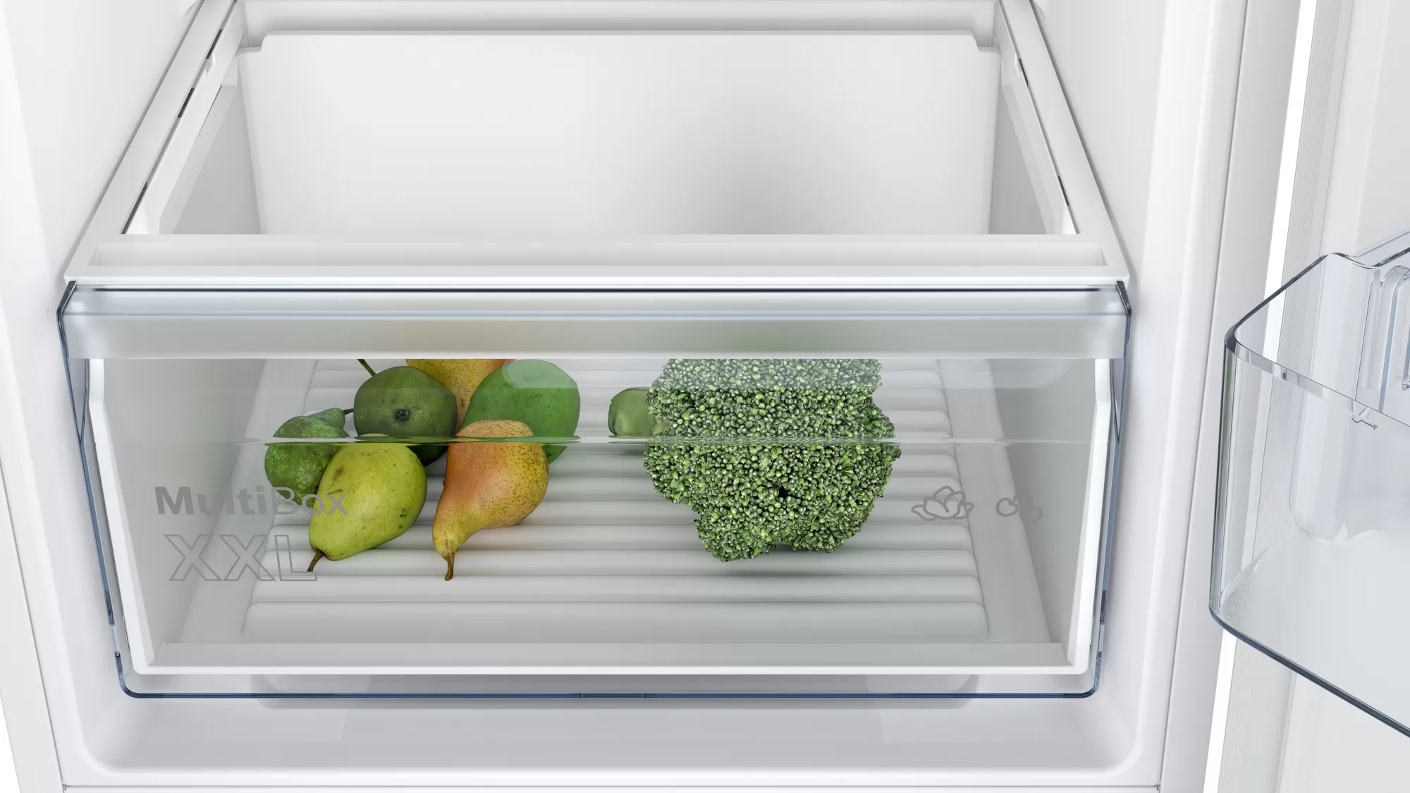 Nahaufnahme einer Kühlschublade mit grünen Birnen und einem Brokkolikopf, beschriftet mit 'Multi Box XXL'.
