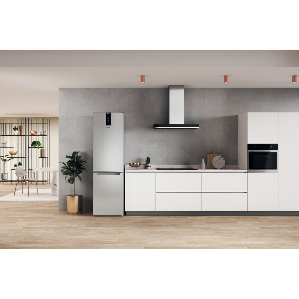 Refrigerador plateado en una cocina moderna. Diseño minimalista. Plantas visibles.