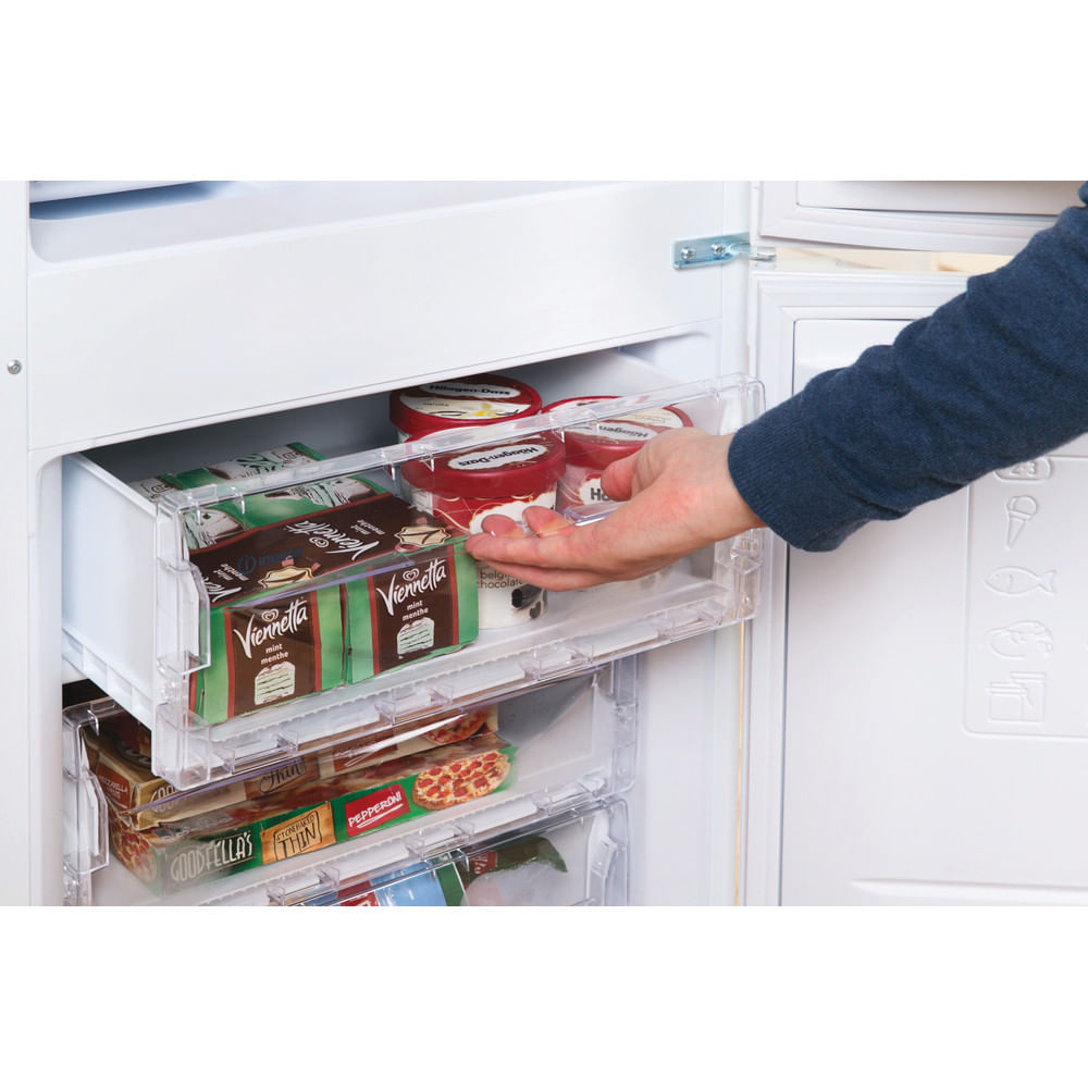 Una mano que llega al compartimento del congelador de un refrigerador para obtener helado.