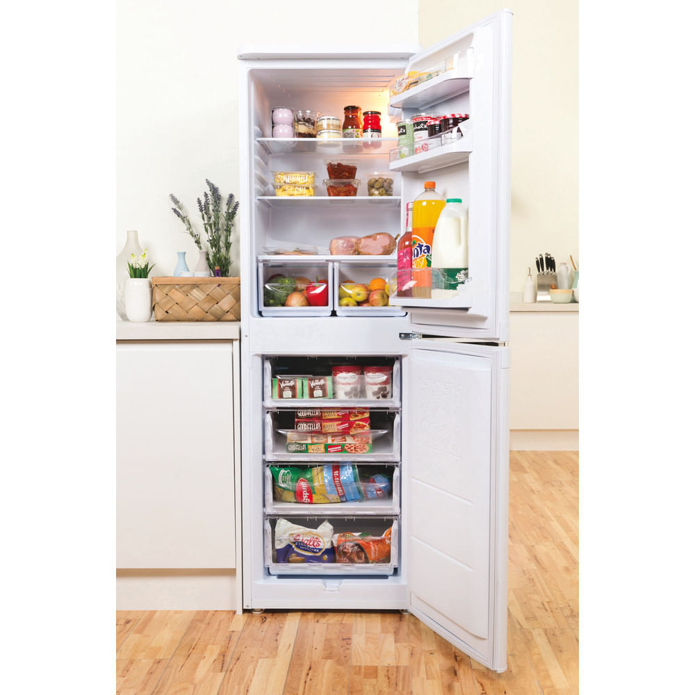 Un refrigerador blanco abierto lleno de alimentos. Cajones con alimentos congelados abajo.