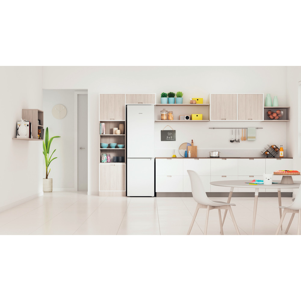 Interior de cocina con refrigerador, gabinetes, mesa, sillas y elementos decorativos.