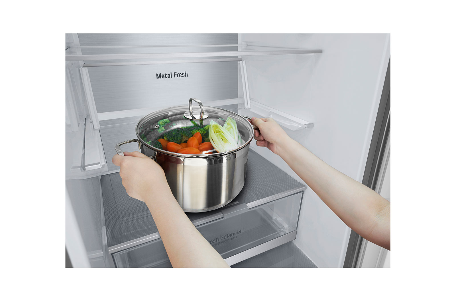 Manos colocando una olla con verduras en un refrigerador. MetalFresh es visible.