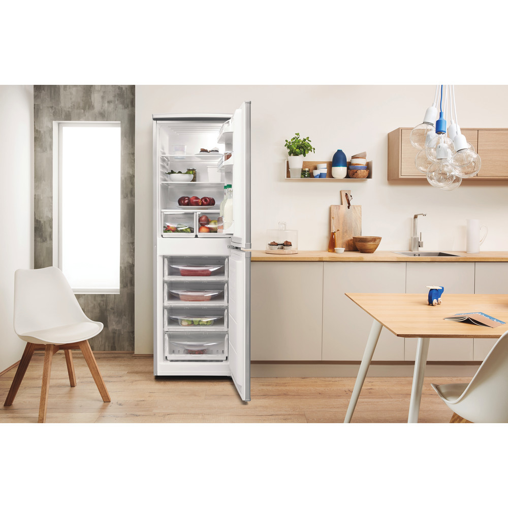 Una cocina moderna con un refrigerador abierto, que muestra estantes y cajones llenos de alimentos y productos.