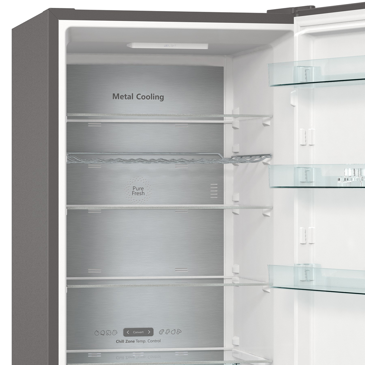 Wnętrze lodówki. Metalowe panele i półki. Jest półka do przechowywania butelek. Drzwi są otwarte.