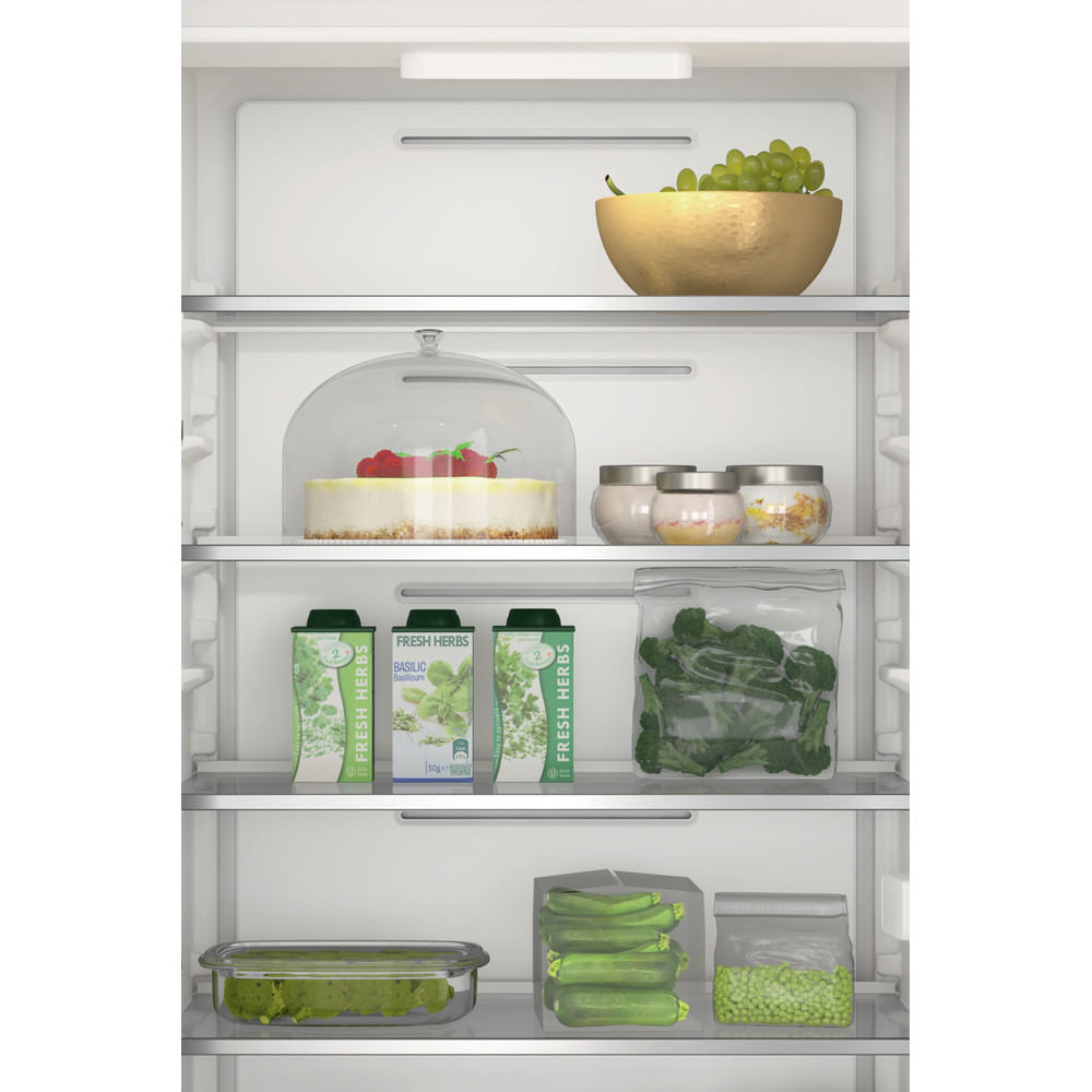 Interior del refrigerador con alimentos, incluidas uvas, hierbas y un pastel bajo una cúpula de cristal.