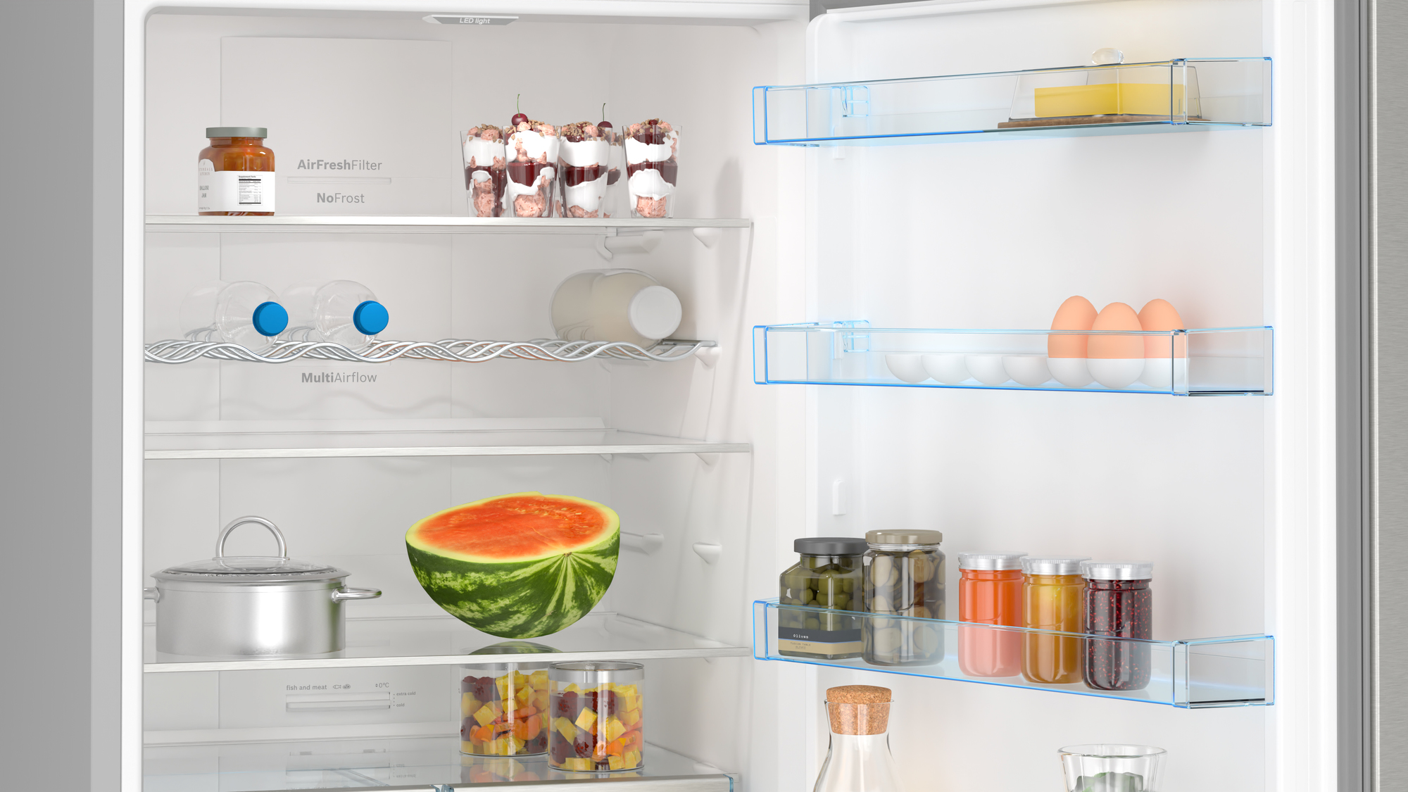 Kühlschrankinnenraum mit verschiedenen Lebensmitteln, darunter Wassermelone, Gläser und Flaschen.