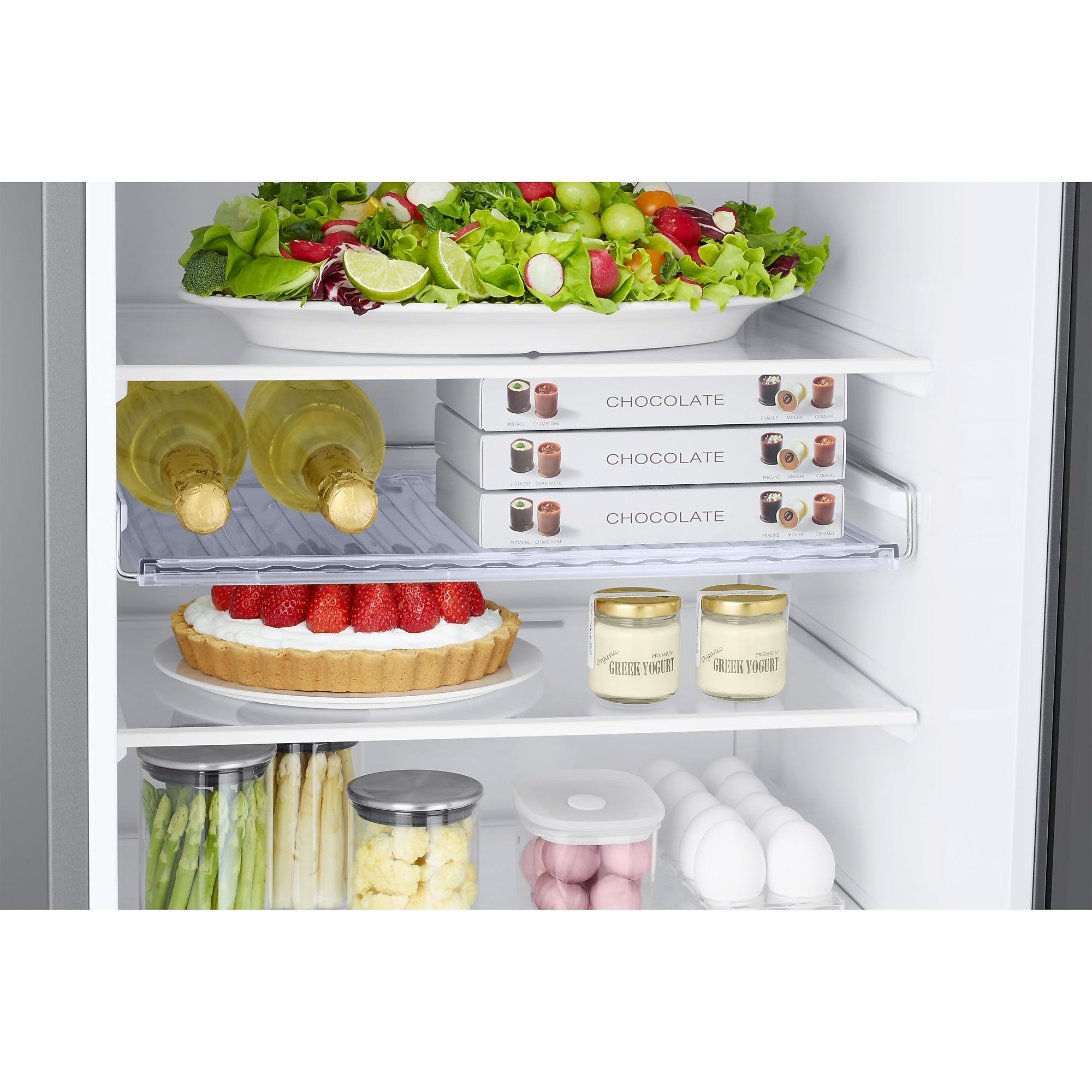 Kühlschrankinnenraum mit Lebensmitteln gefüllt: Salat, Pralinen, Wein, Kuchen, Joghurt, Spargel und Eier. Geordnete Regale.