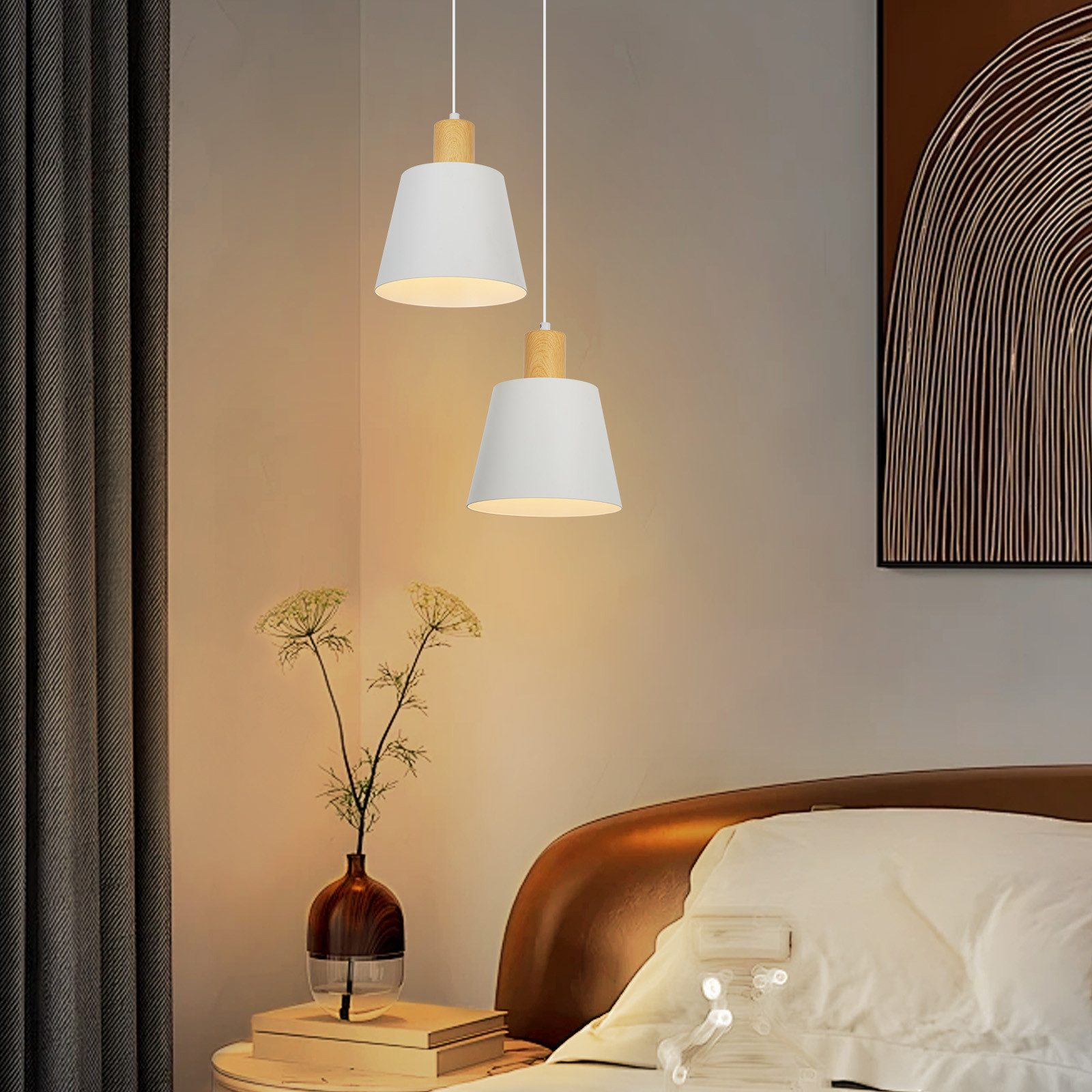 Camera da letto con due lampade a sospensione bianche, un letto e un vaso con fiori su un comodino.