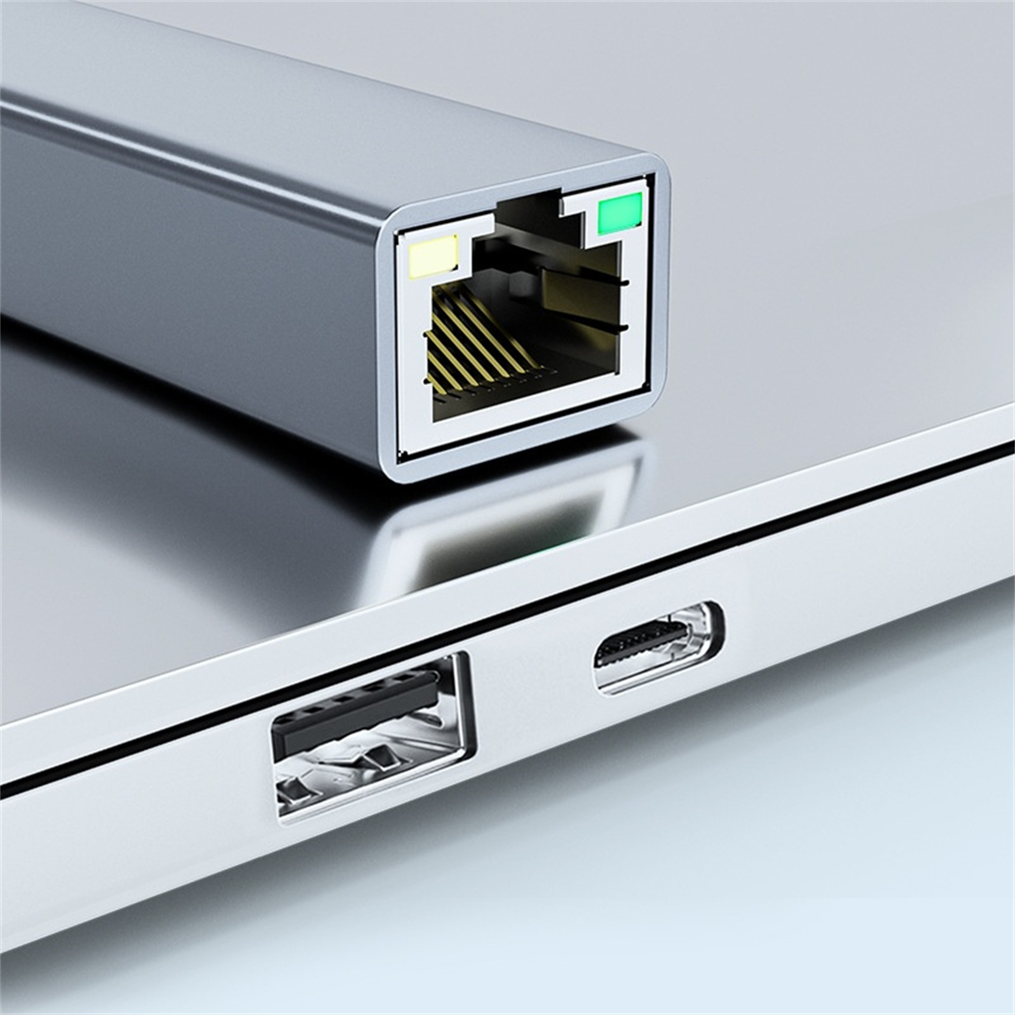 Ein silberner USB-C-Adapter, der in einen Laptop eingesteckt ist. Der Adapter hat einen Ethernet-Anschluss.
