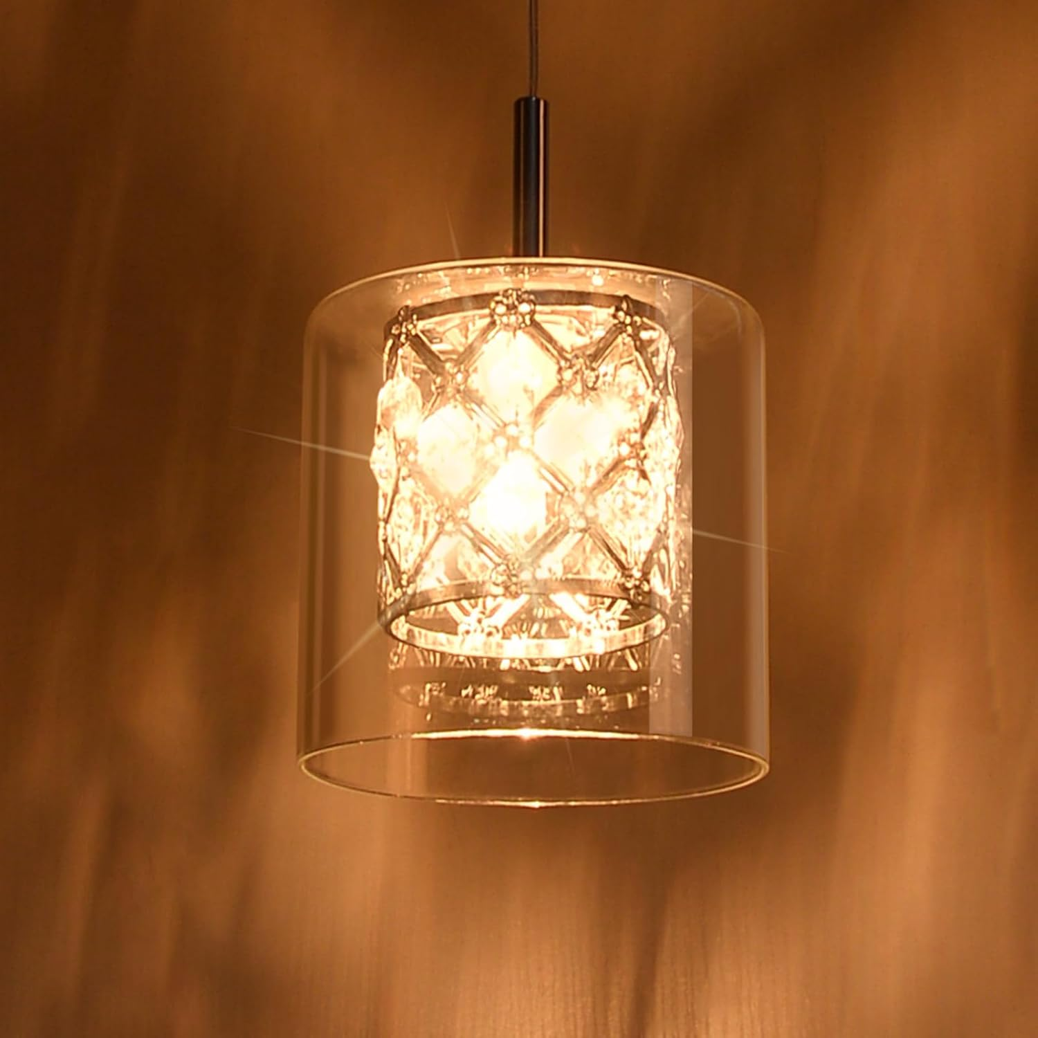 Eine Pendelleuchte mit klarem Glasschirm und kristallartigem Innenraum. Warmes Licht.