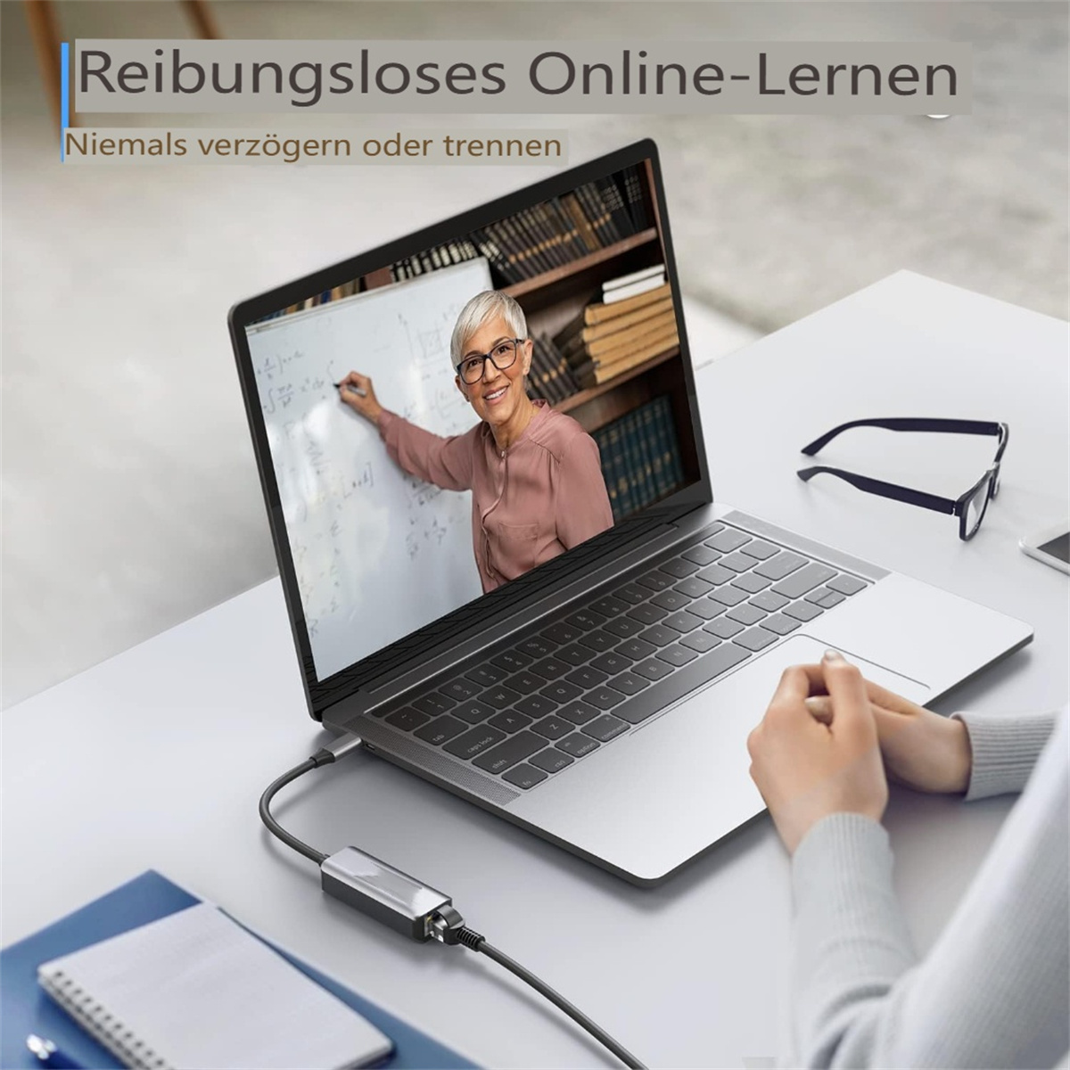 Ein Laptop-Bildschirm, der eine unterrichtende Frau zeigt, mit Kabel und Metalladapter.