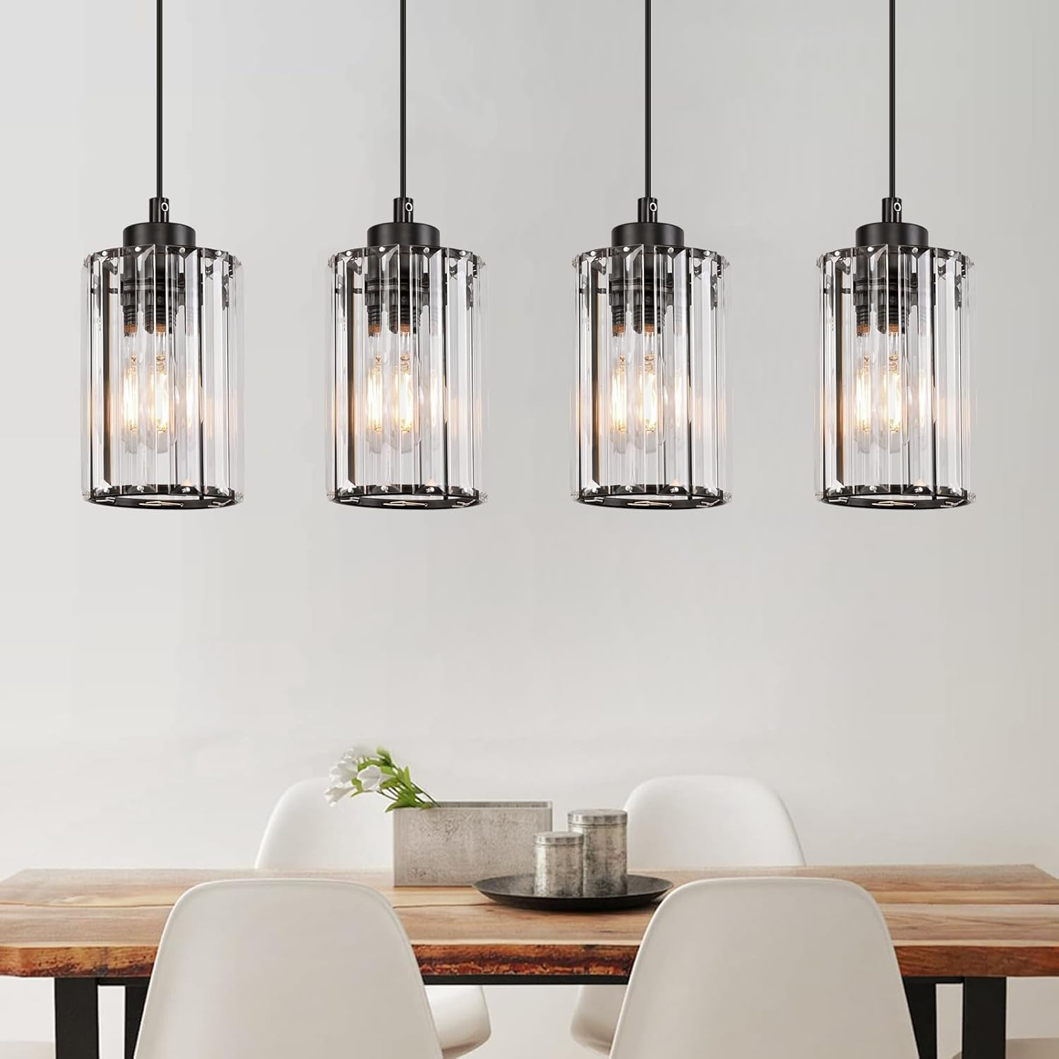 Comedor con mesa de madera y cuatro lámparas colgantes de cristal sobre ella.